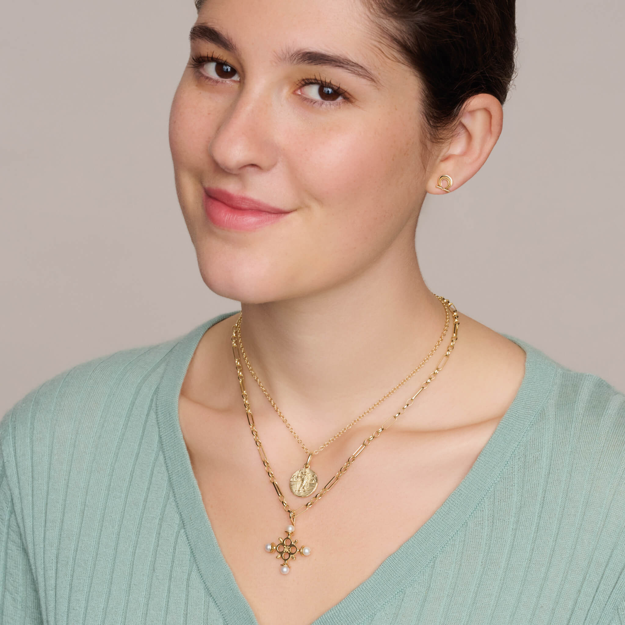 Model wearing a handcrafted cross necklace pendant in yellow gold with pearl.