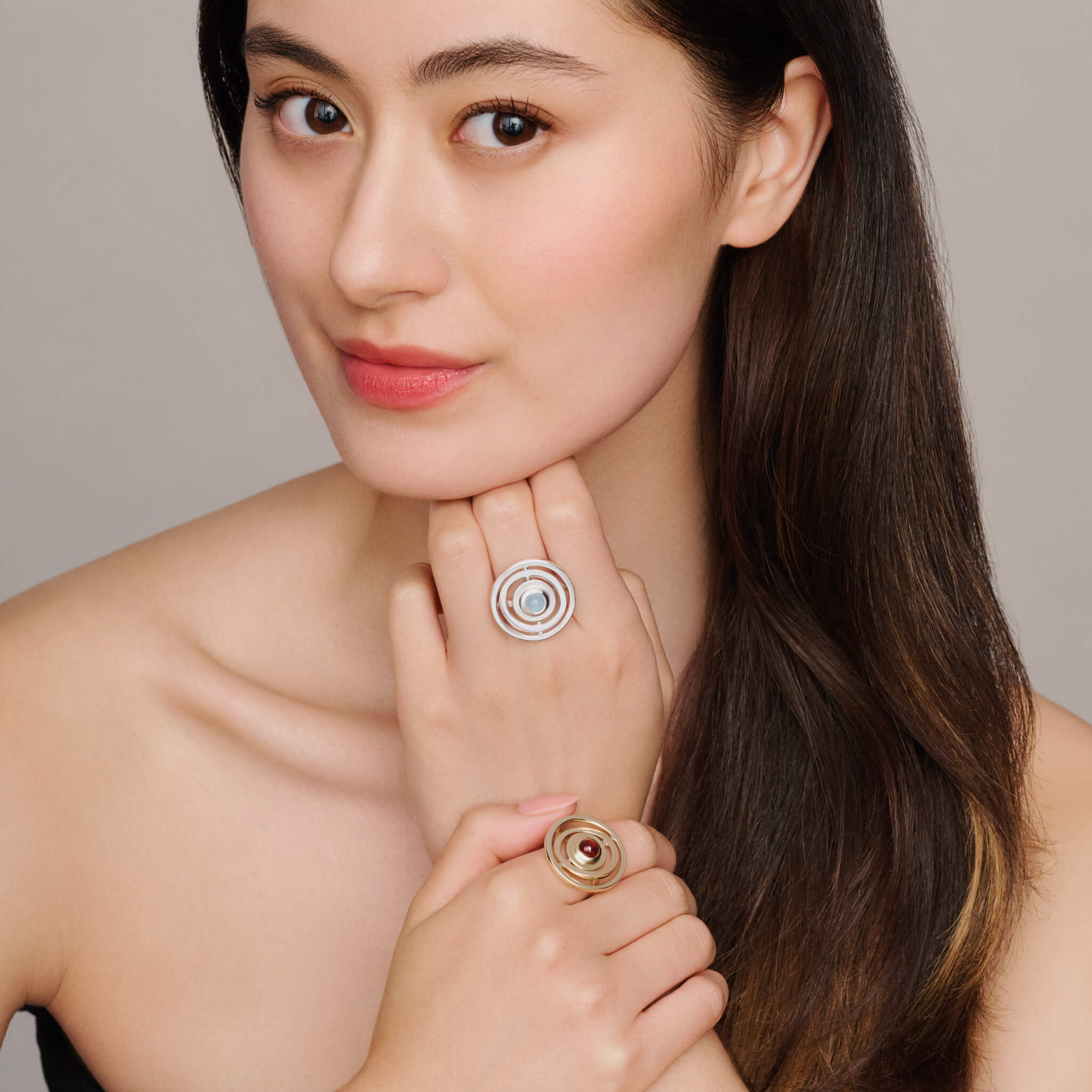 Model wears handcrafted 9ct yellow gold cocktail ring featuring three concentric circles with movement and a central cabochon red garnet.