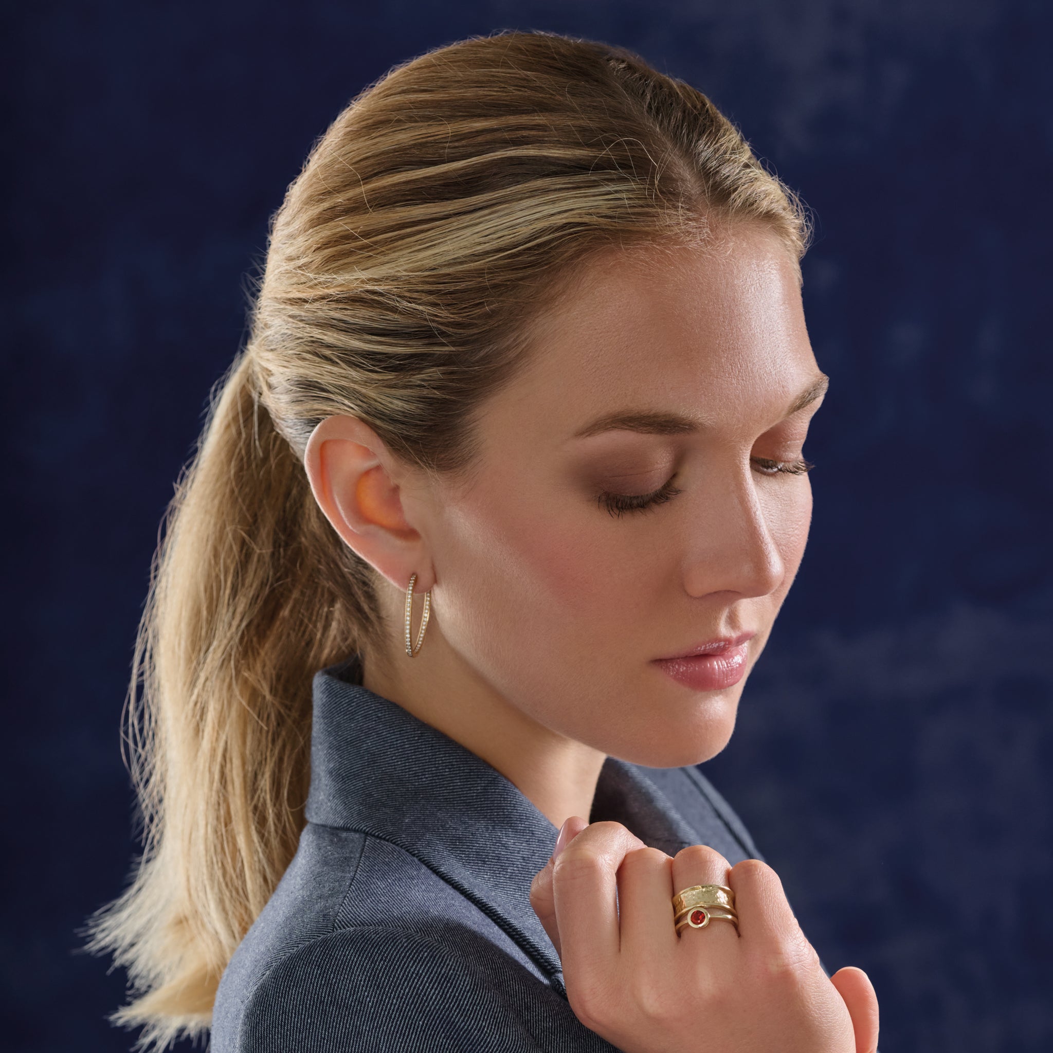 Model wearing handcrafted 18ct yellow gold oval hoop earrings with diamonds.