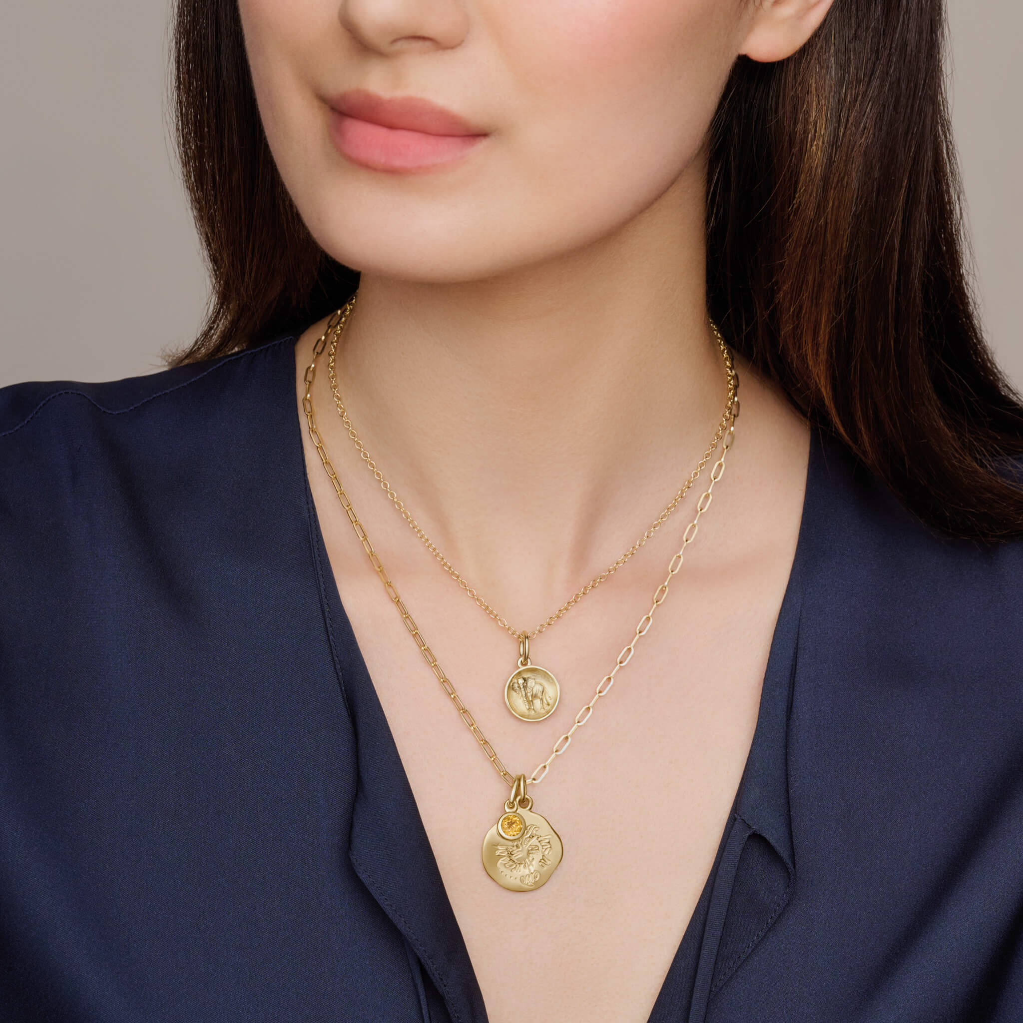 Model wearing a handcrafted round yellow gold pendant necklace engraved with a quote on courage.