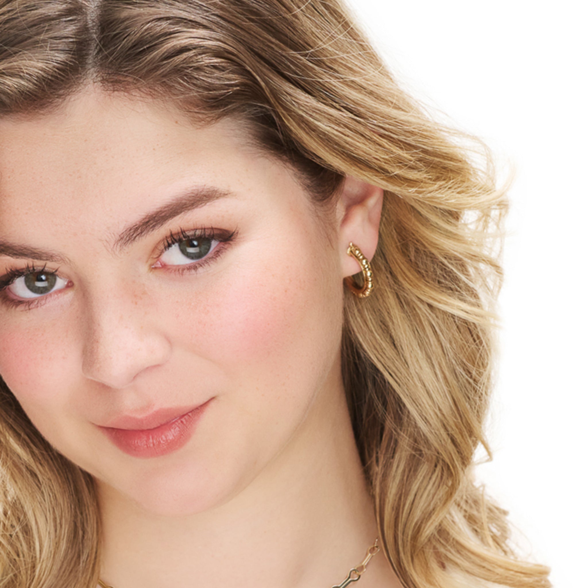 Model wearing handcrafted yellow gold hoop earrings featuring small gold beads.