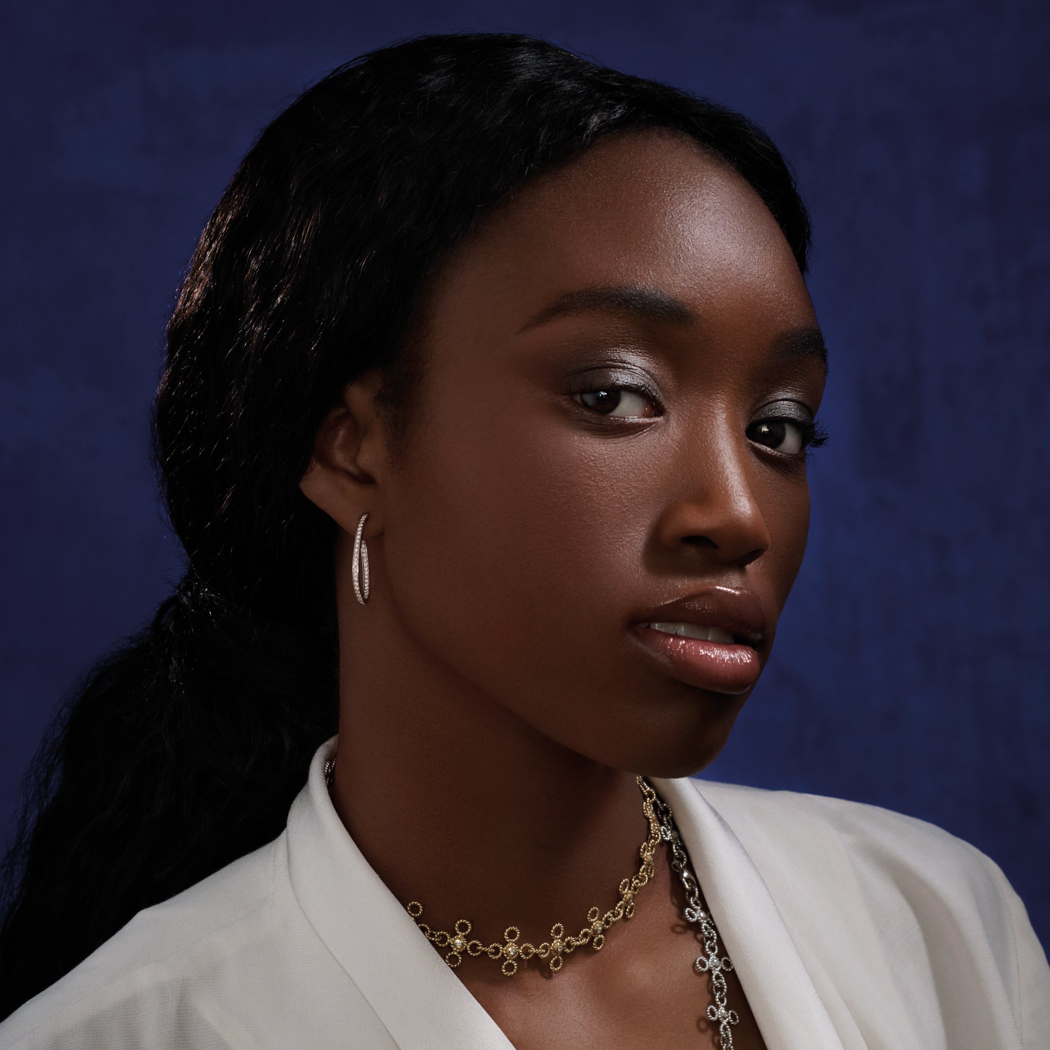 Model wearing handcrafted 18ct white gold oval hoop earrings with diamonds.