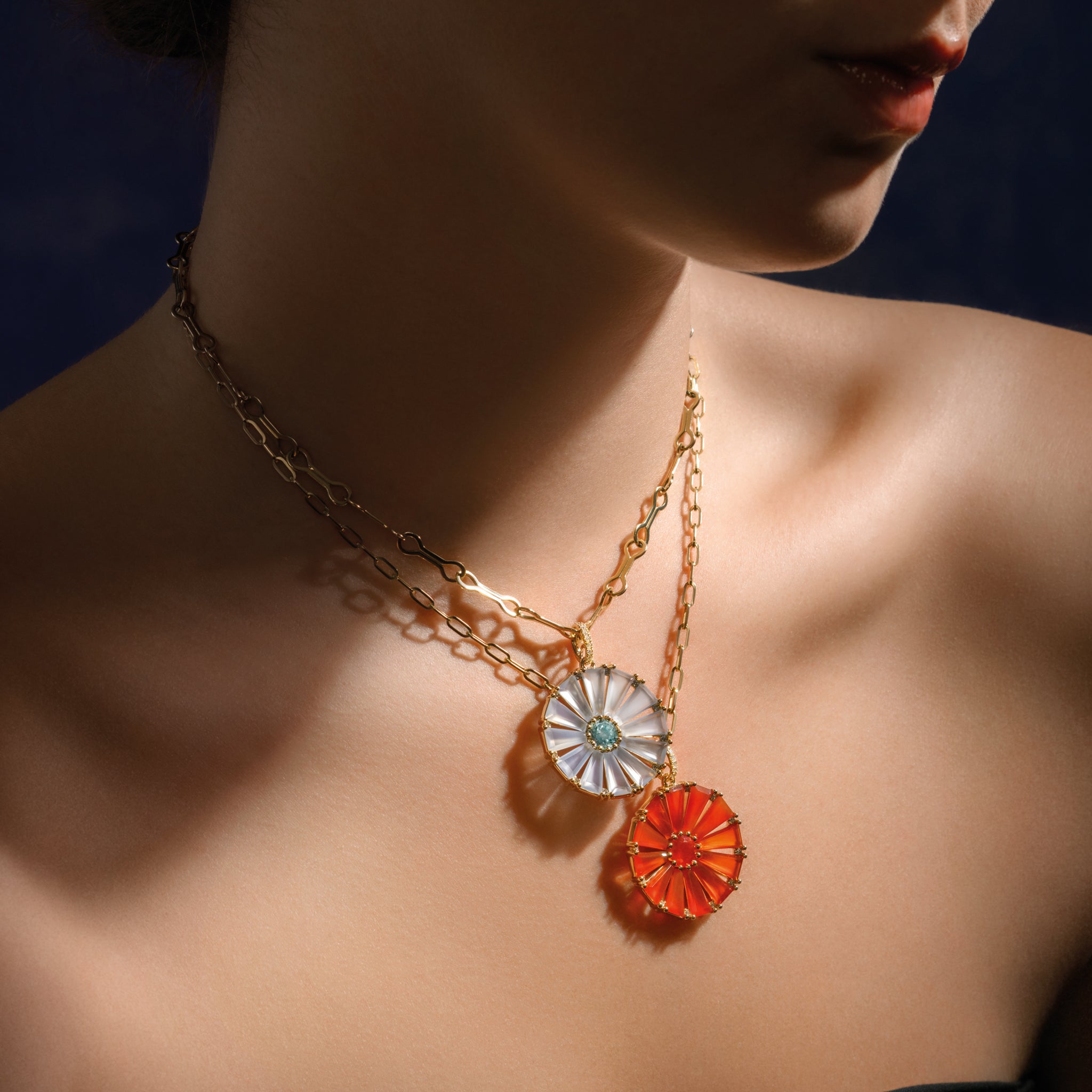 Model wearing a handcrafted yellow gold circular necklace pendant with baguette cut blue chalcedony, blue topaz and diamond gemstones.