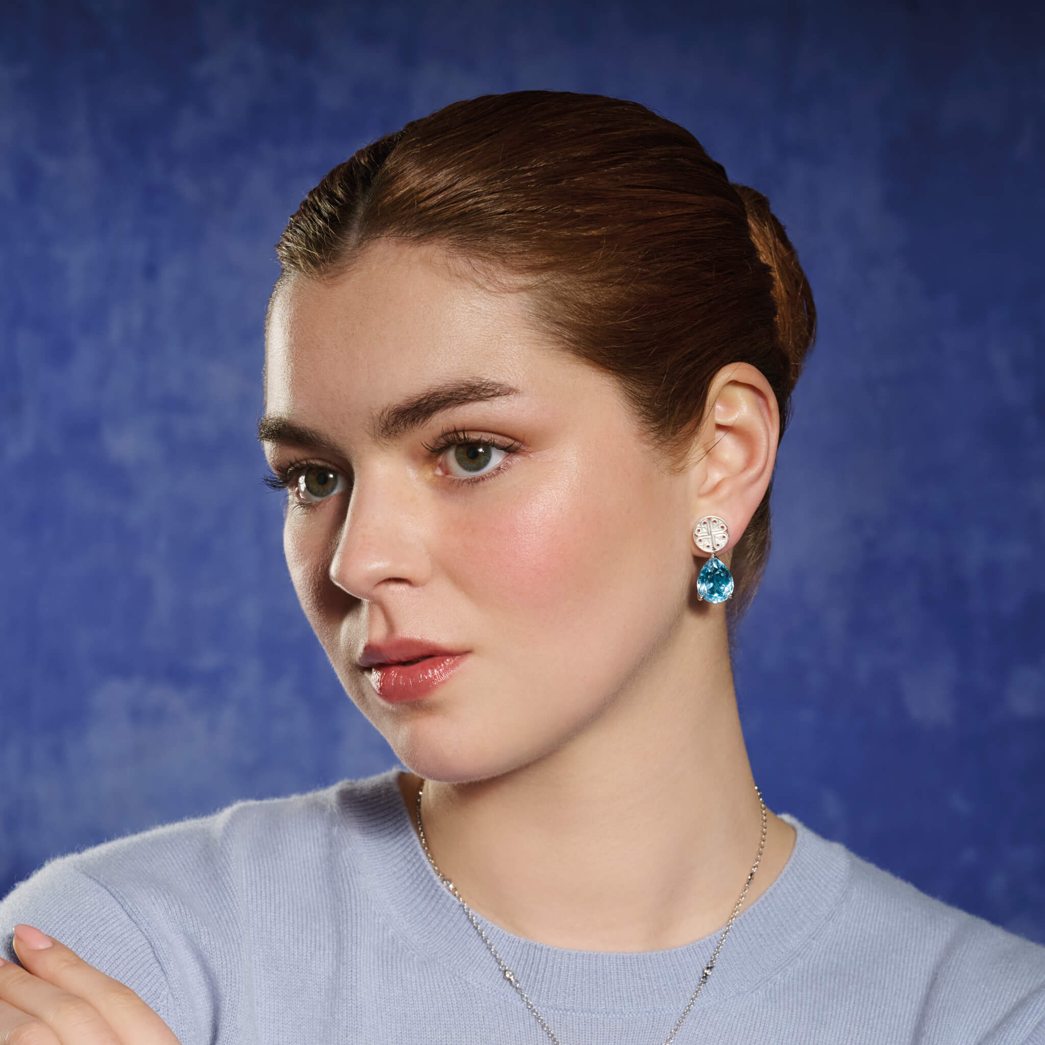 Model wears handcrafted silver circular earring studs with a cross-like motif in the centre.