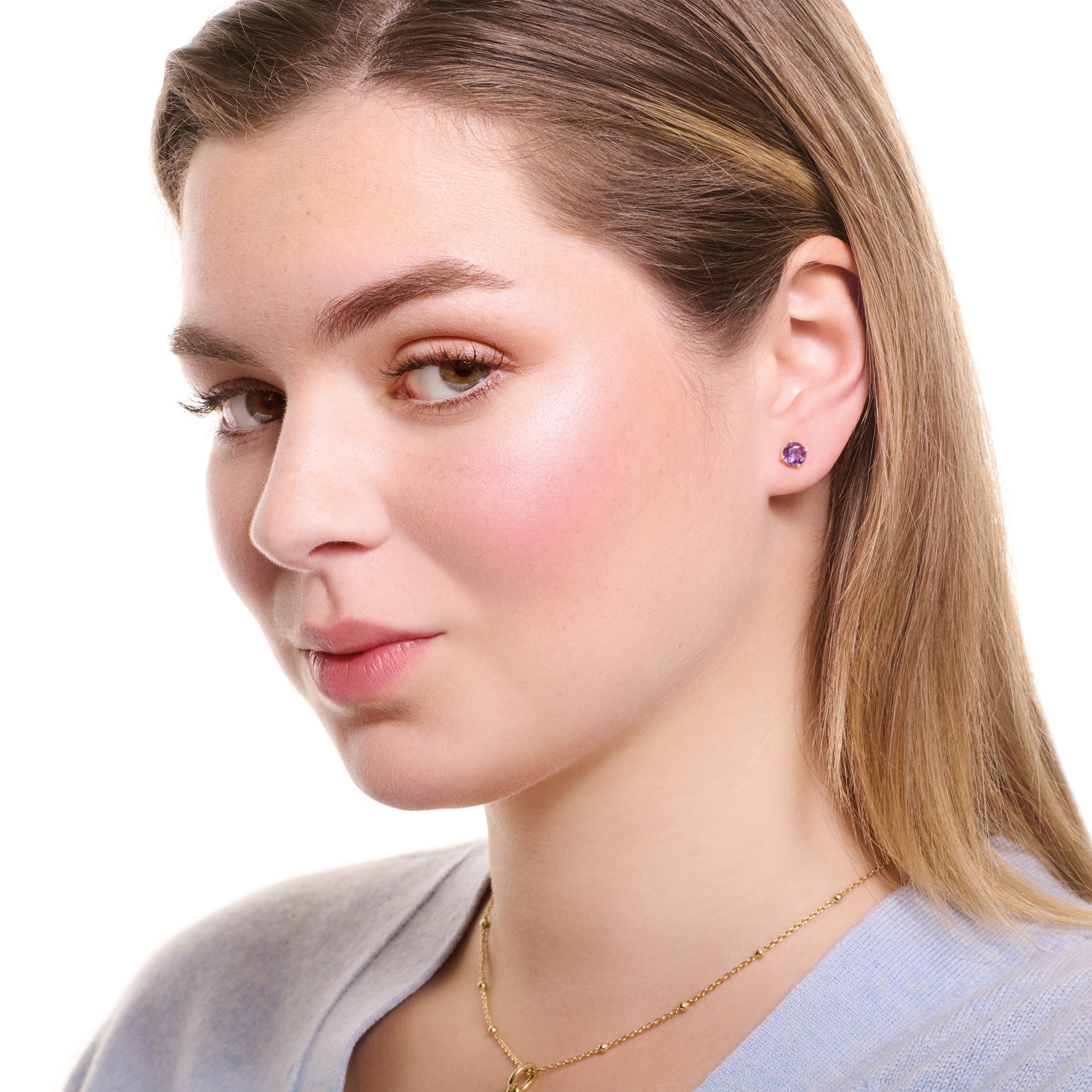 Model wearing handcrafted stud earrings in precious metal with round precious stones.