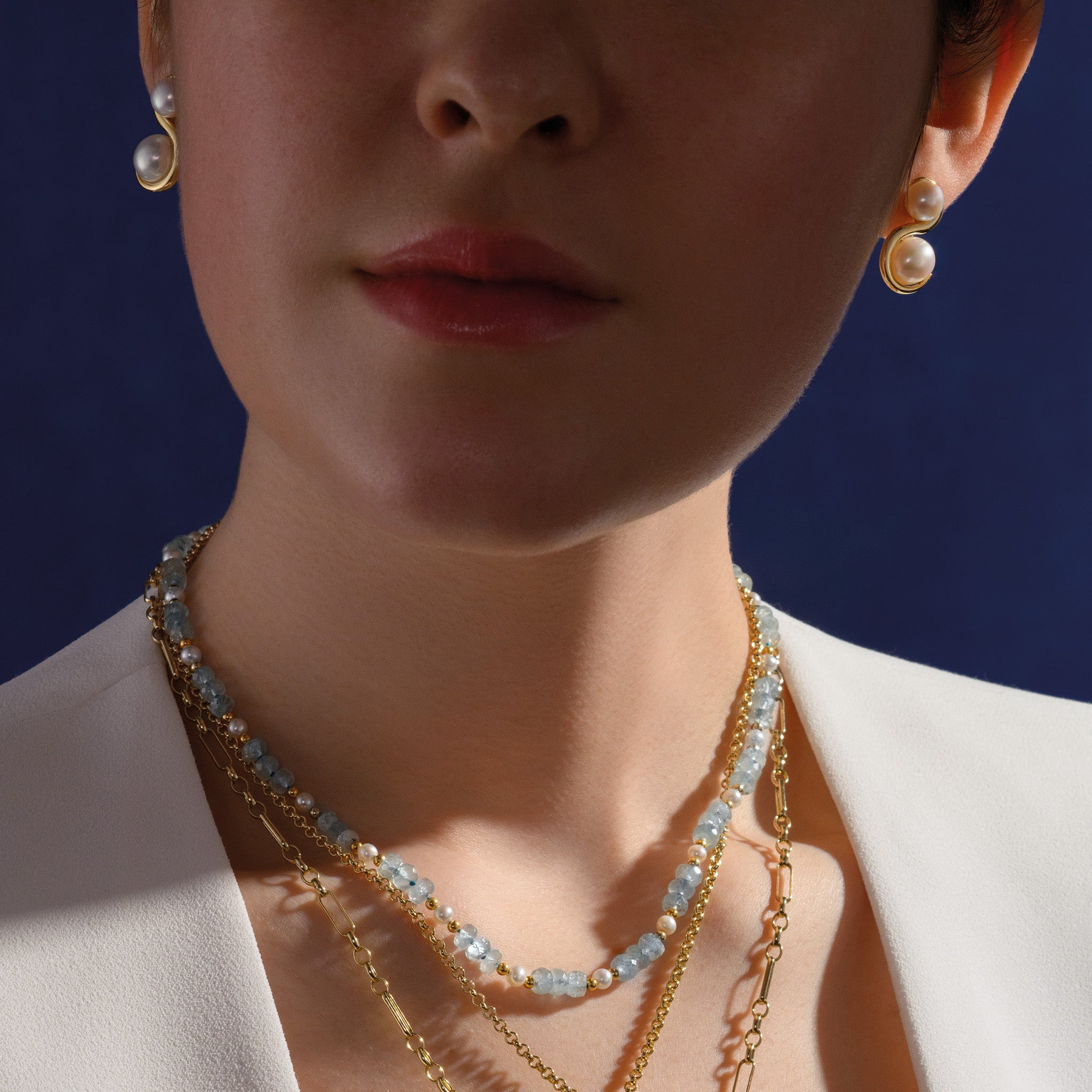 Model wearing a handcrafted yellow gold necklace with aquamarines and pearls.