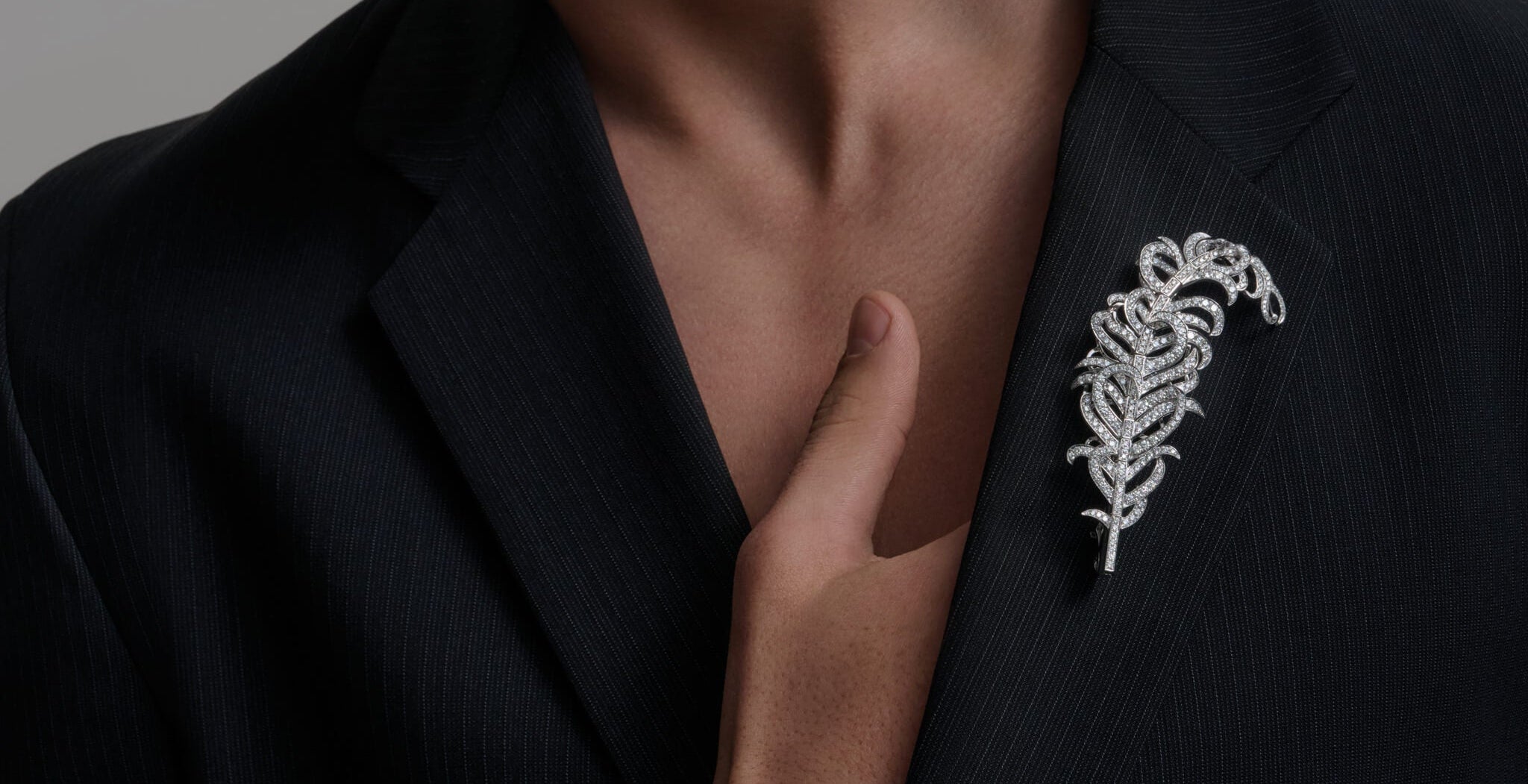 Feather Plume Masterpiece on a dark blazer.
