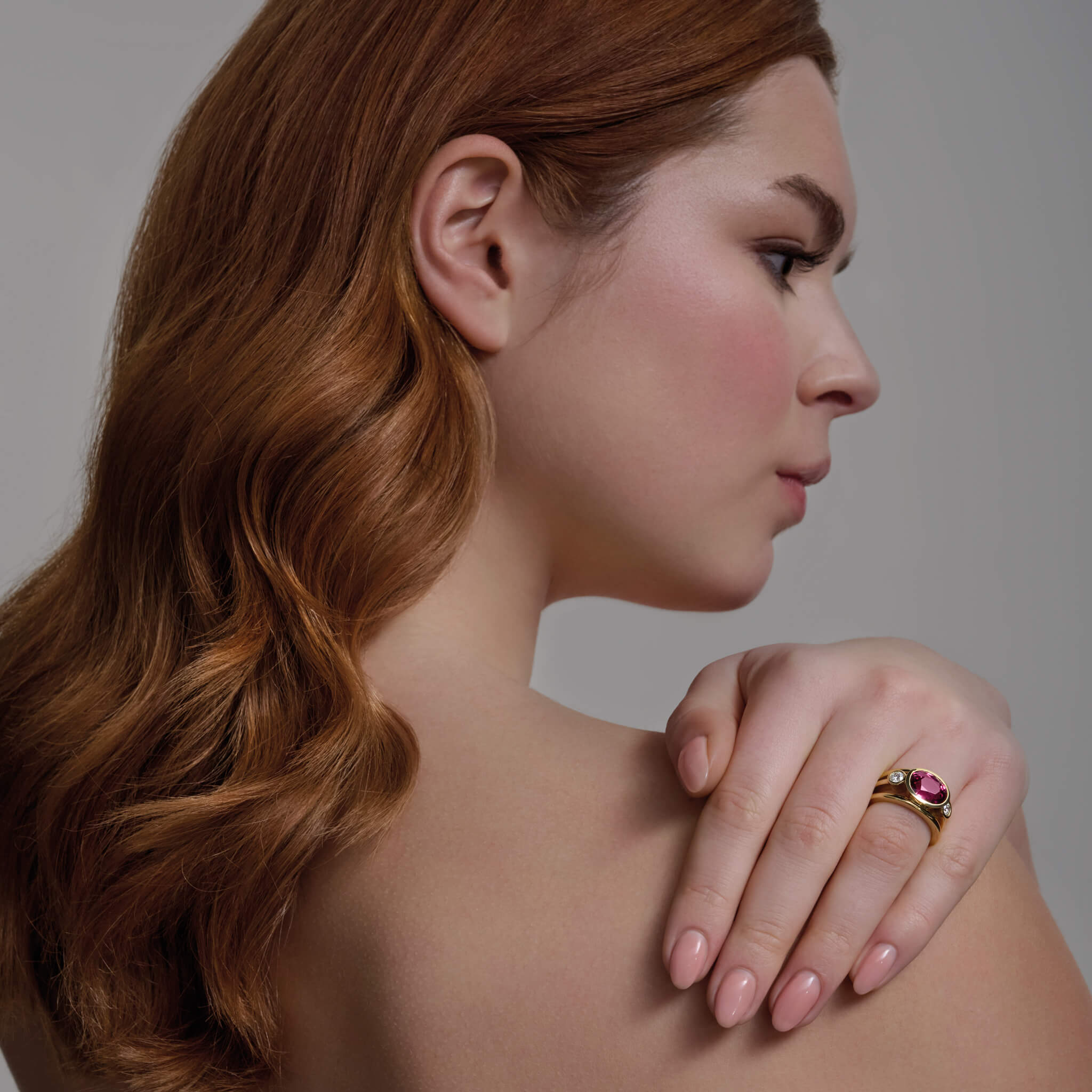 Model wears handcrafted 18ct yellow gold ring with a central pink umbilite garnet, the birthstone of January, flanked by two round diamonds.