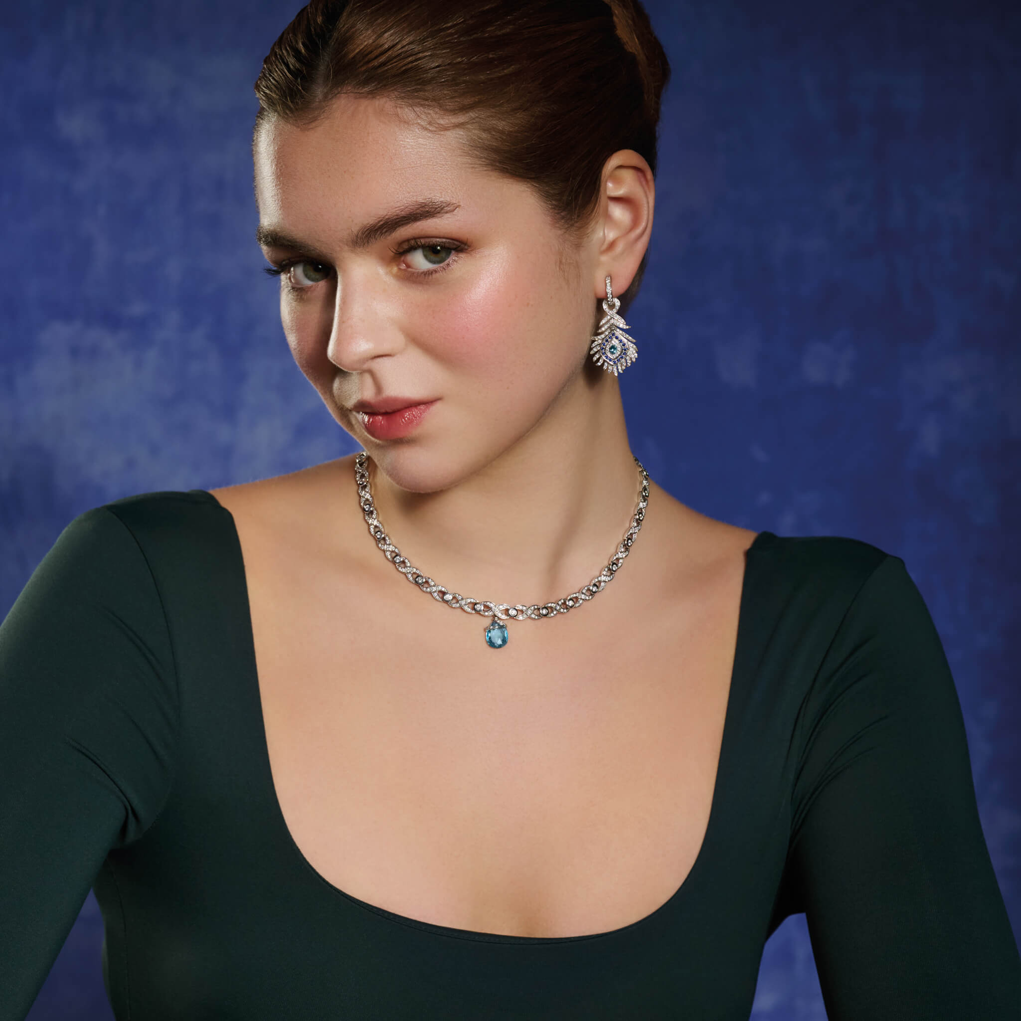 Model wearing a handcrafted 18ct white gold necklace with a looping pattern, set with round cut diamonds.