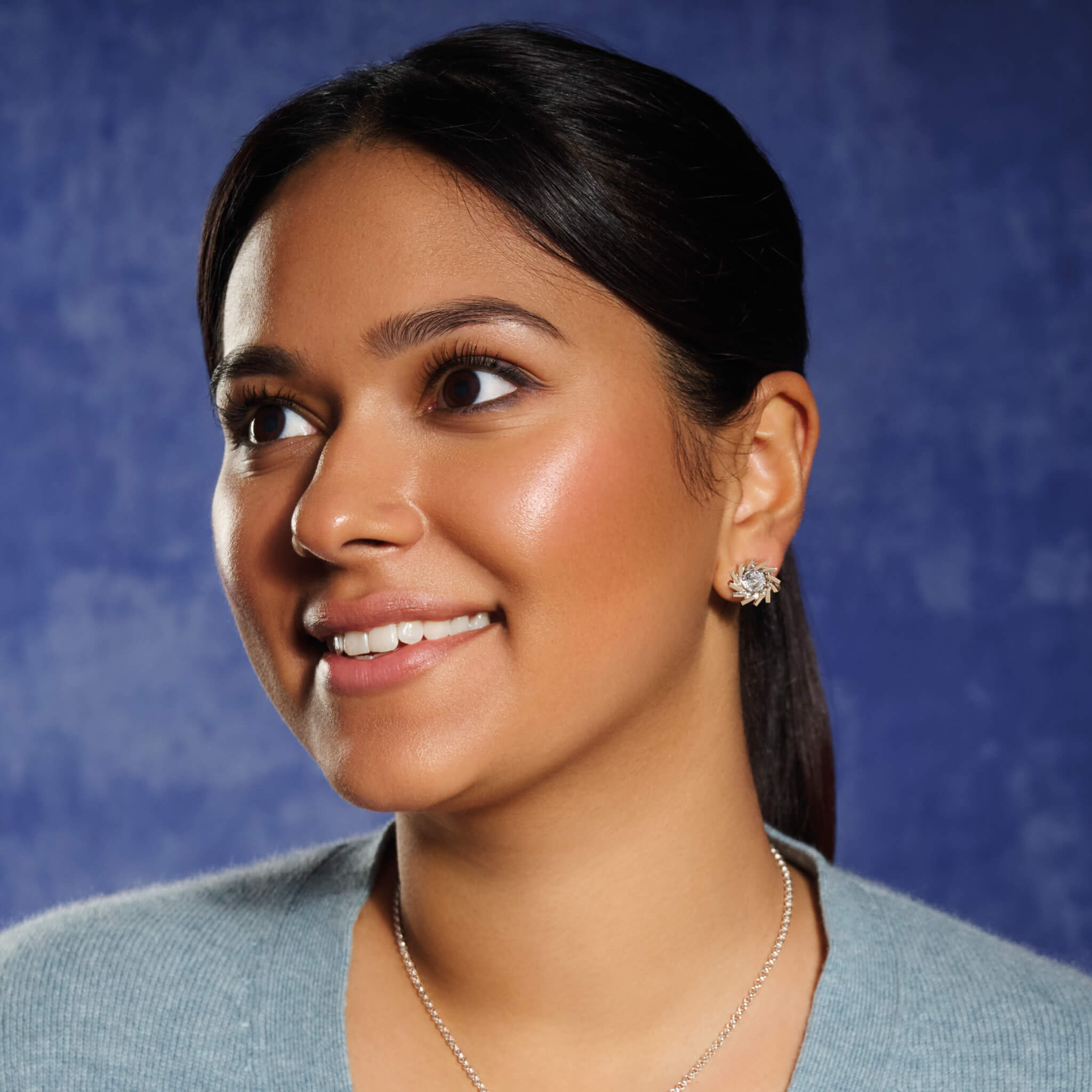 Model wears handcrafted silver earring halos featuring a circular shape of diagonal lines.