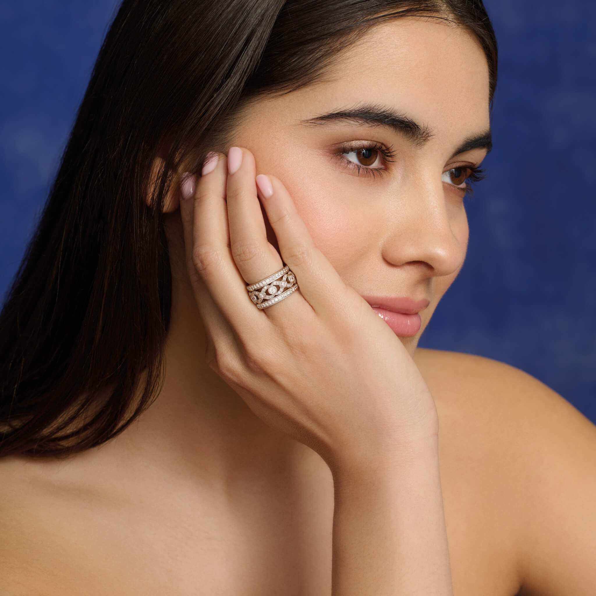 Model wearing handcrafted 18ct white gold eternity ring with a dual band with a looping pattern in the middle, set with round-cut diamonds.
