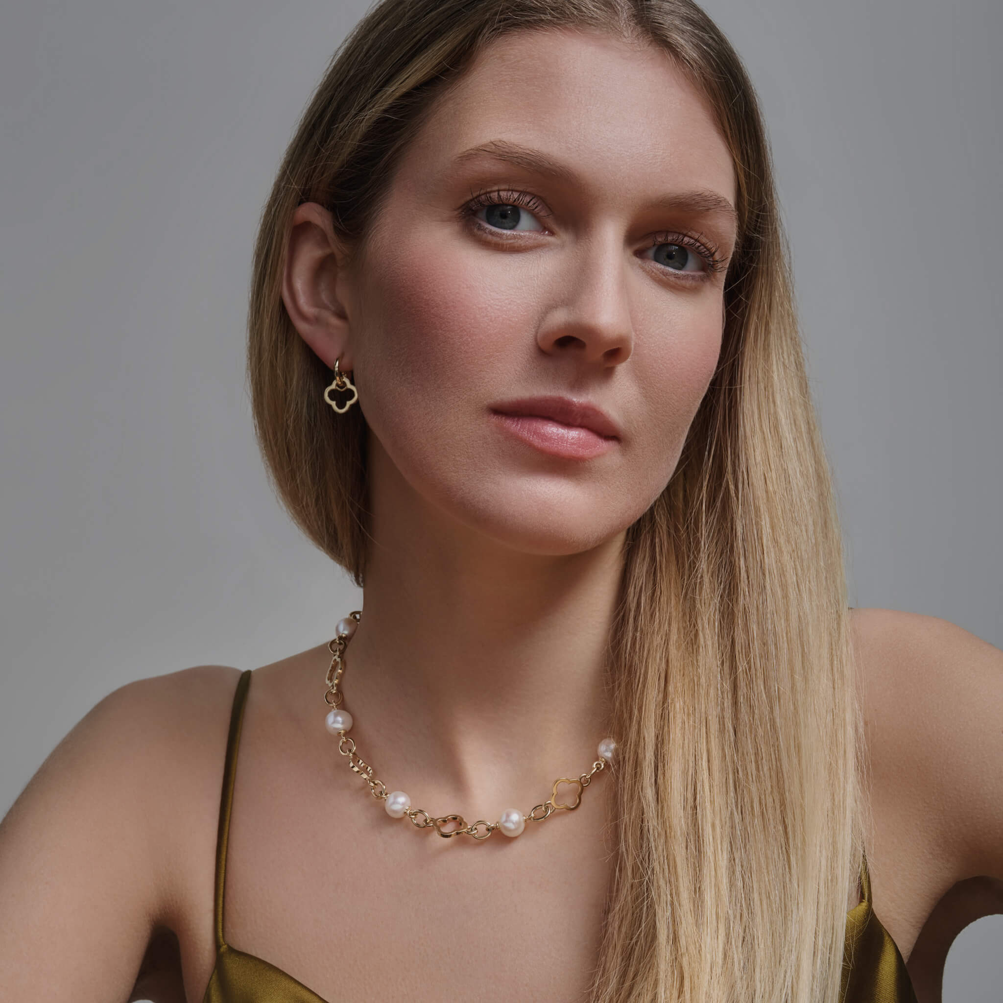 Model wears handcrafted yellow gold necklace with star-shaped links, spaced with pearls, birthstone of June.