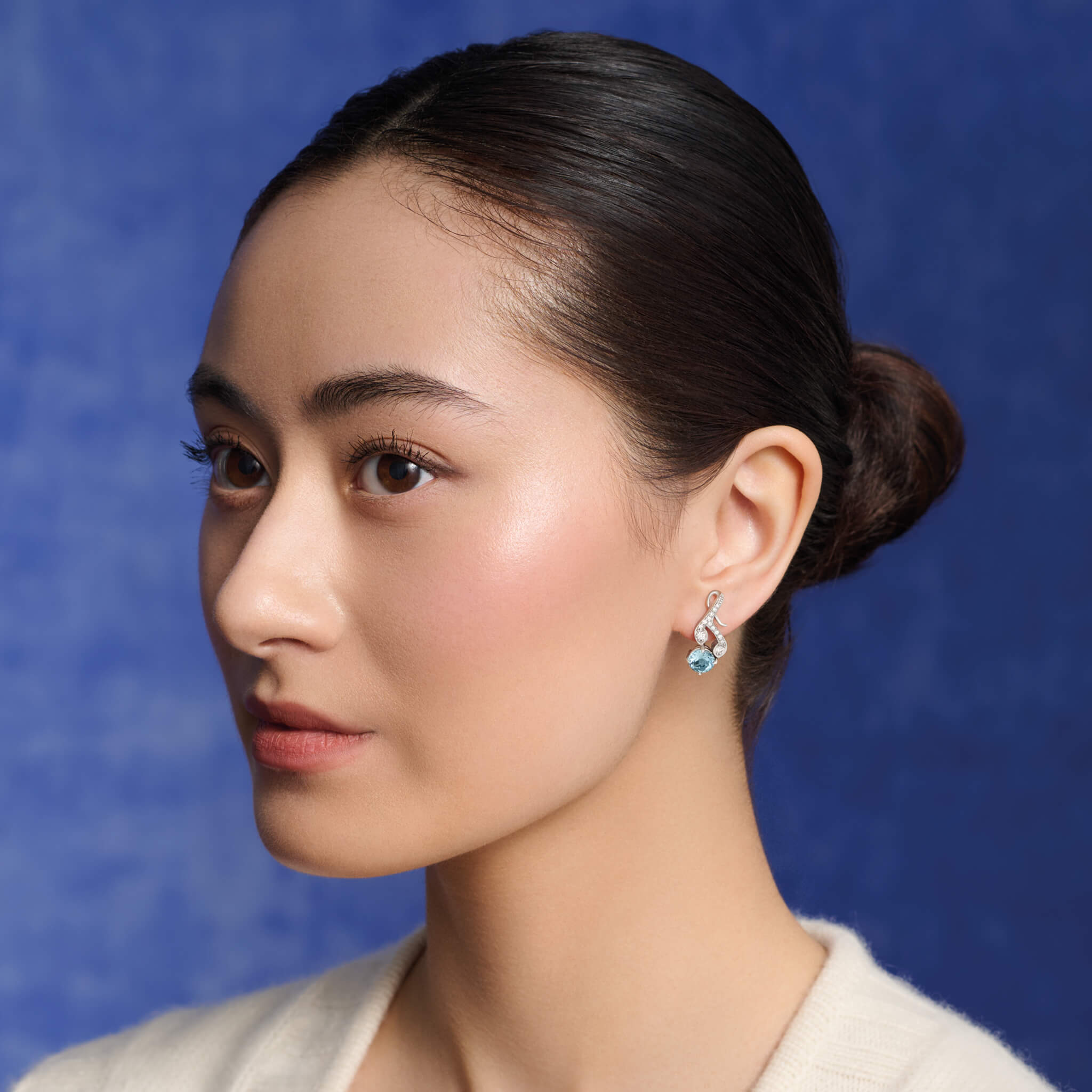 Model wears handcrafted 18ct white gold earrings with diamonds and a aquamarine drop in the shape of a sprig of rosemary.
