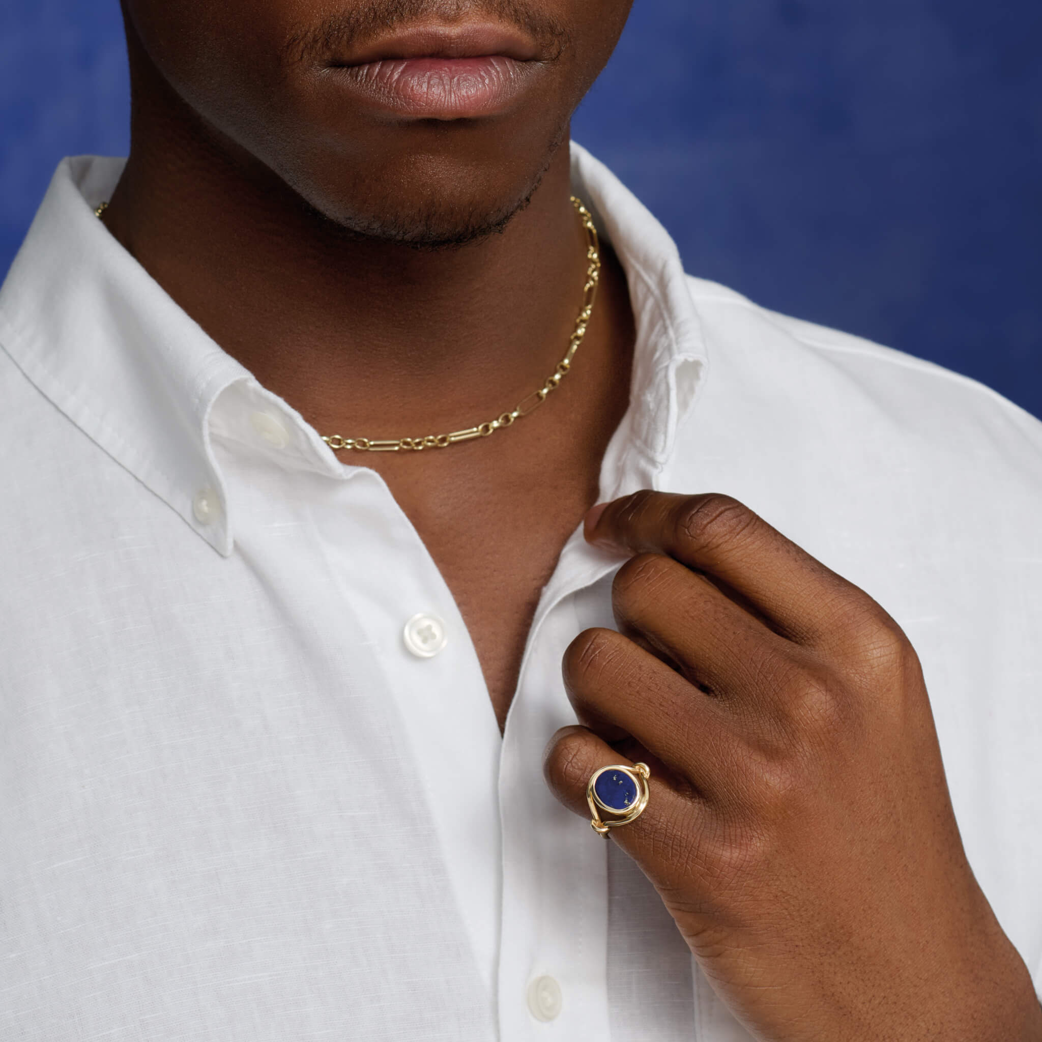 Model wears handcrafted yellow gold signet ring featuring a smooth, round central disc of lapis lazuli with sleek, curved band accents.