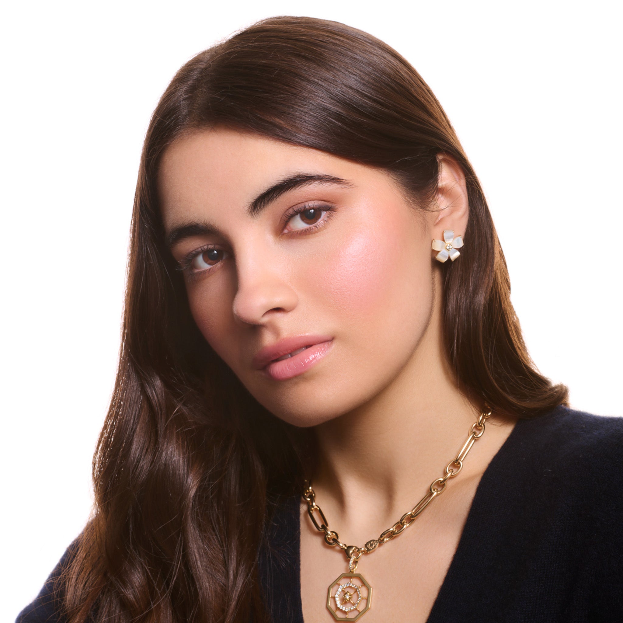 model wears handcrafted yellow gold flower earring studs featuring five mother of pearl petals and a central diamond.