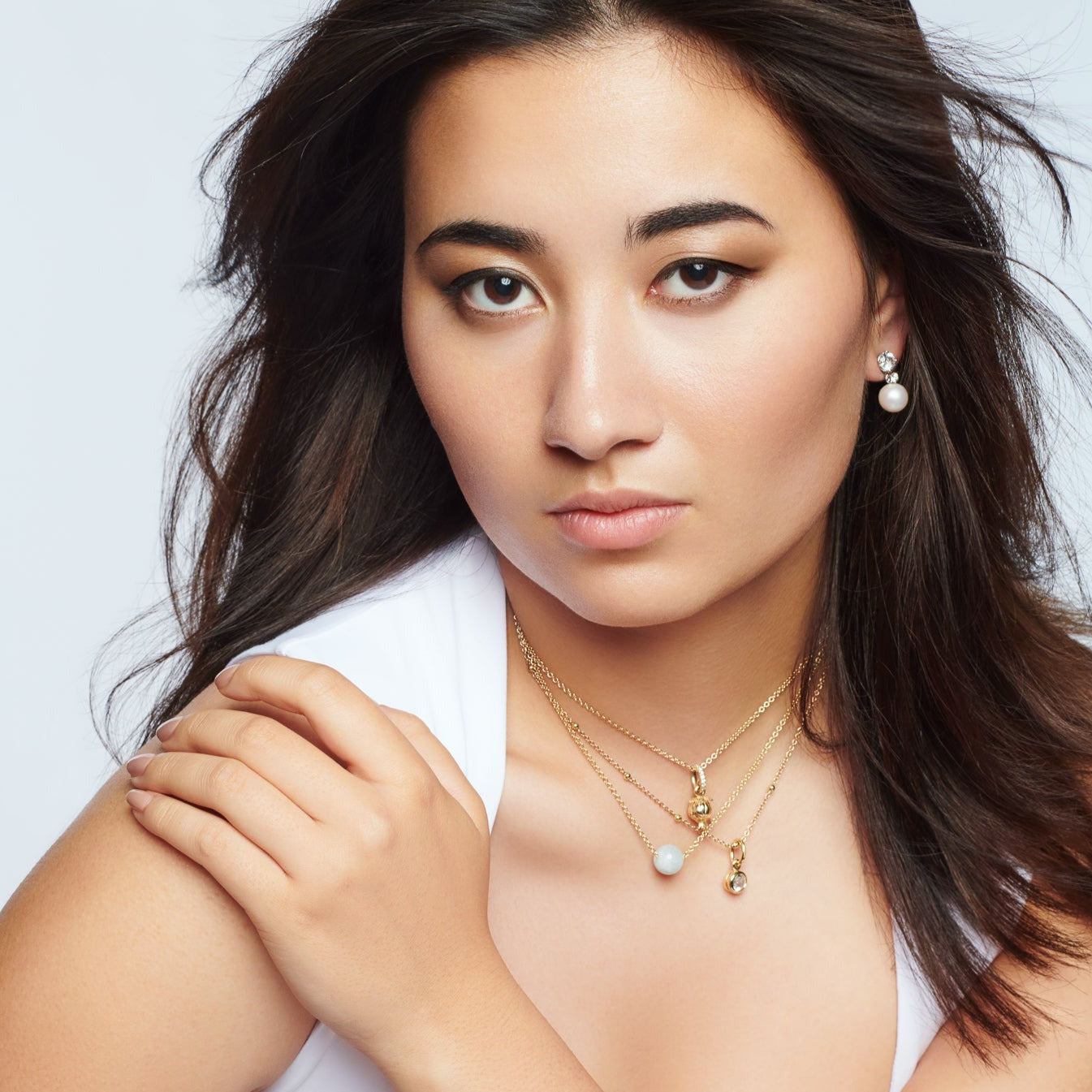 Model wearing a handcrafted necklace in yellow gold featuring a round pearl and a yellow gold pomegranate shaped necklace pendant.