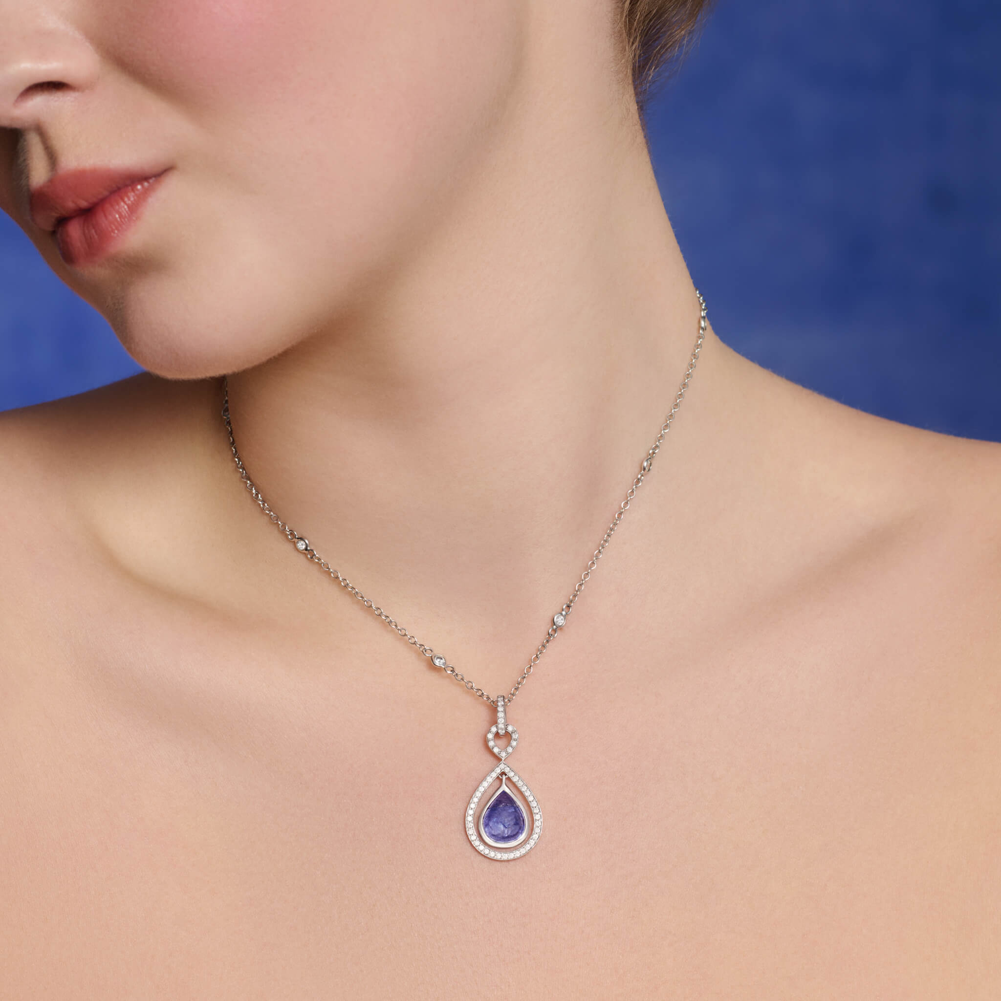 Models wears handcrafted 18ct white gold pendant featuring a pear shape cabochon tanzanite gemstone with diamonds, inspired by Japanese elegance, birthstone of December.