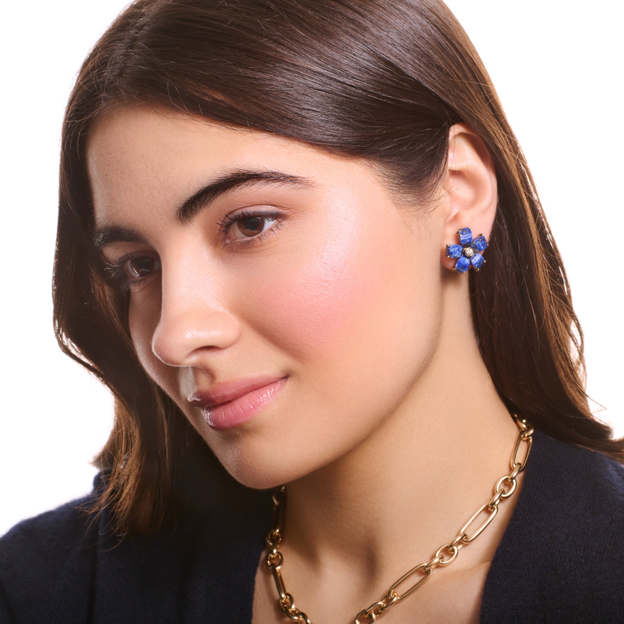 Model wearing handcrafted yellow gold flower earring studs featuring five lapis lazuli petals and a central diamond.
