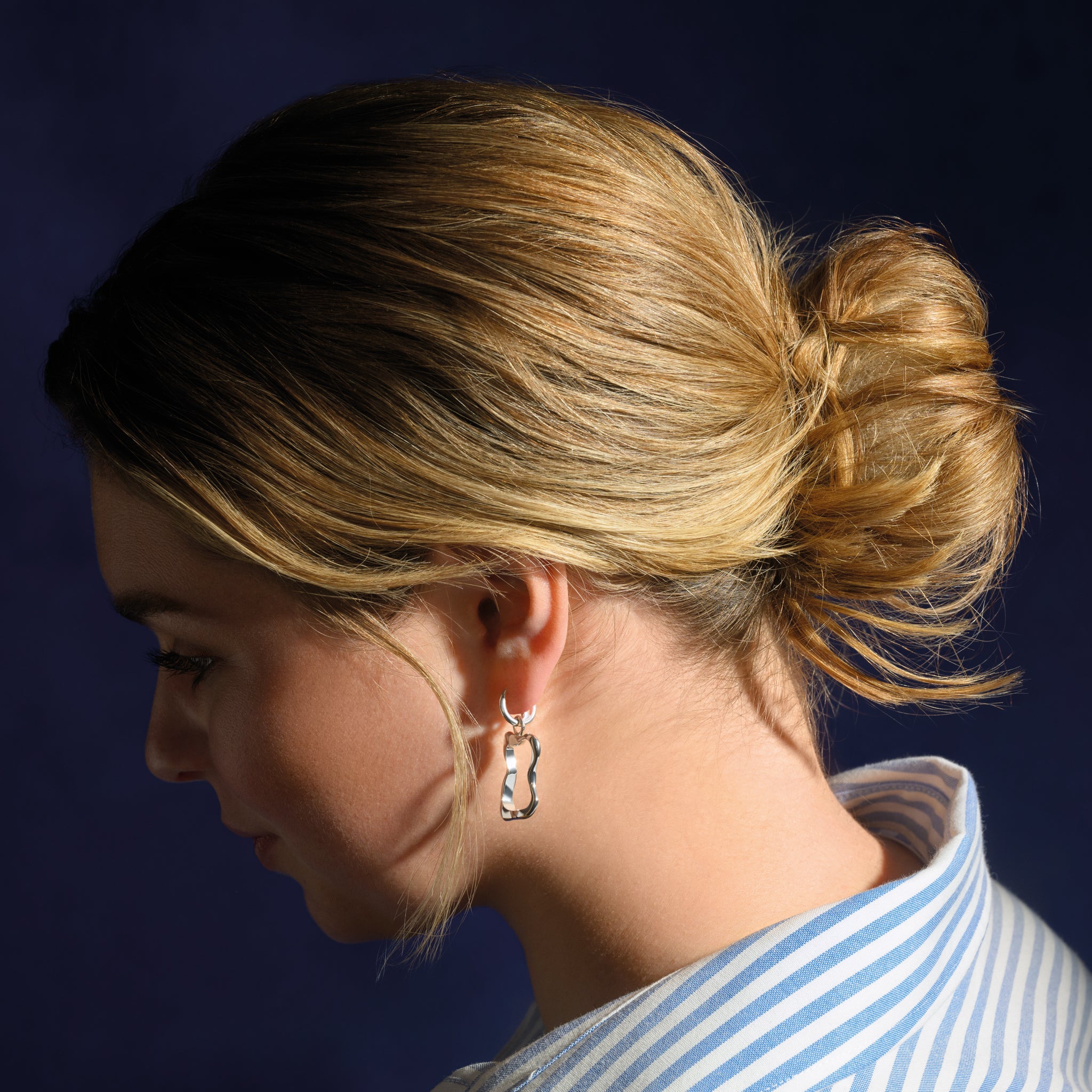 Model wearing handcrafted sterling silver earring drops feauring the outline of the french pastries: pain au chocolat.