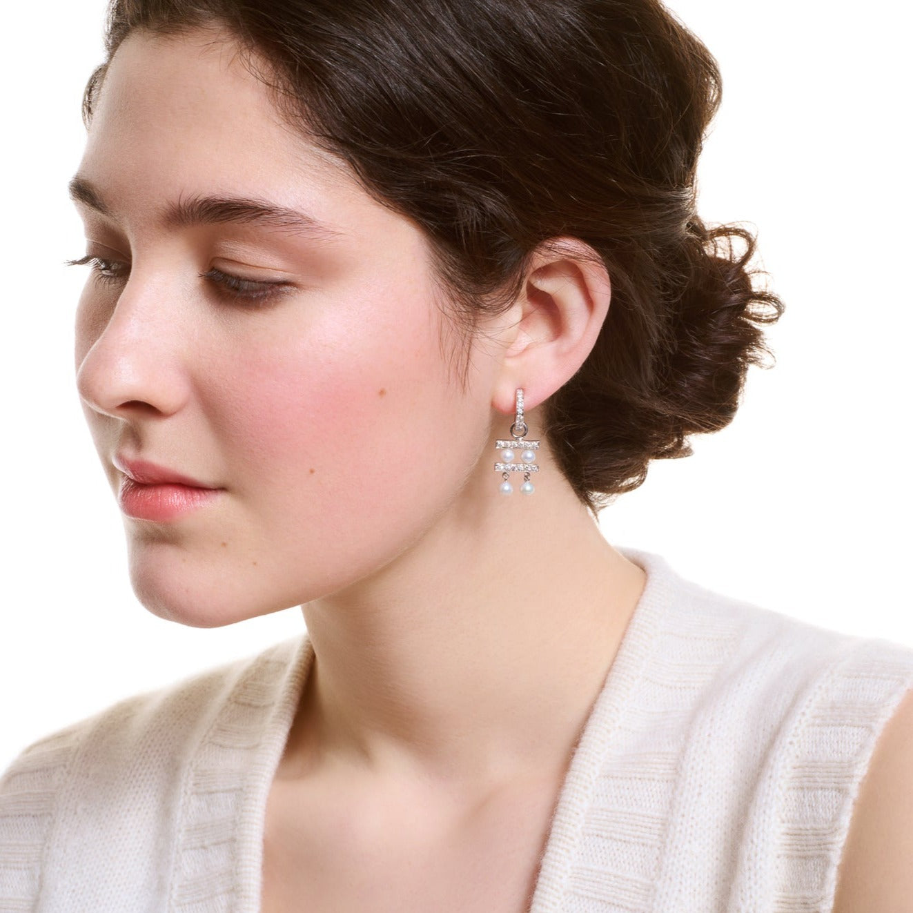 Model wearing handcrafted 18ct white gold earring drops with two tiers of pearls separated by delicate gold lines adorned with diamond pav?.