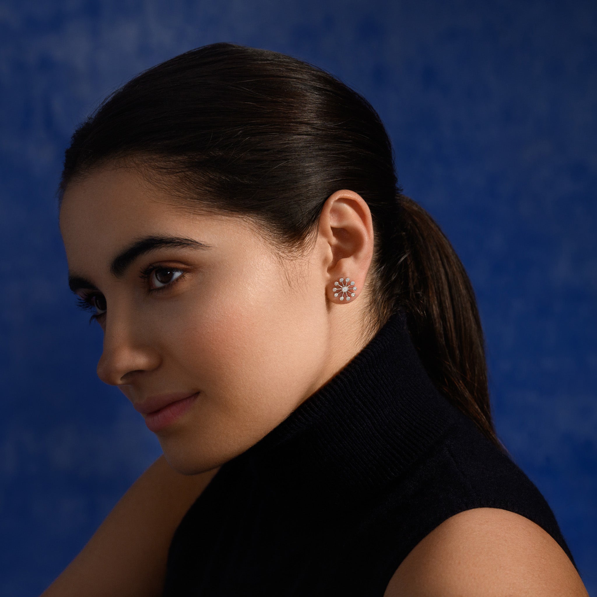 Model wearing handcrafted 18ct white gold earrings inspired by the delicate spurs of an astrantia flower, with diamonds set at the tip of each spur.