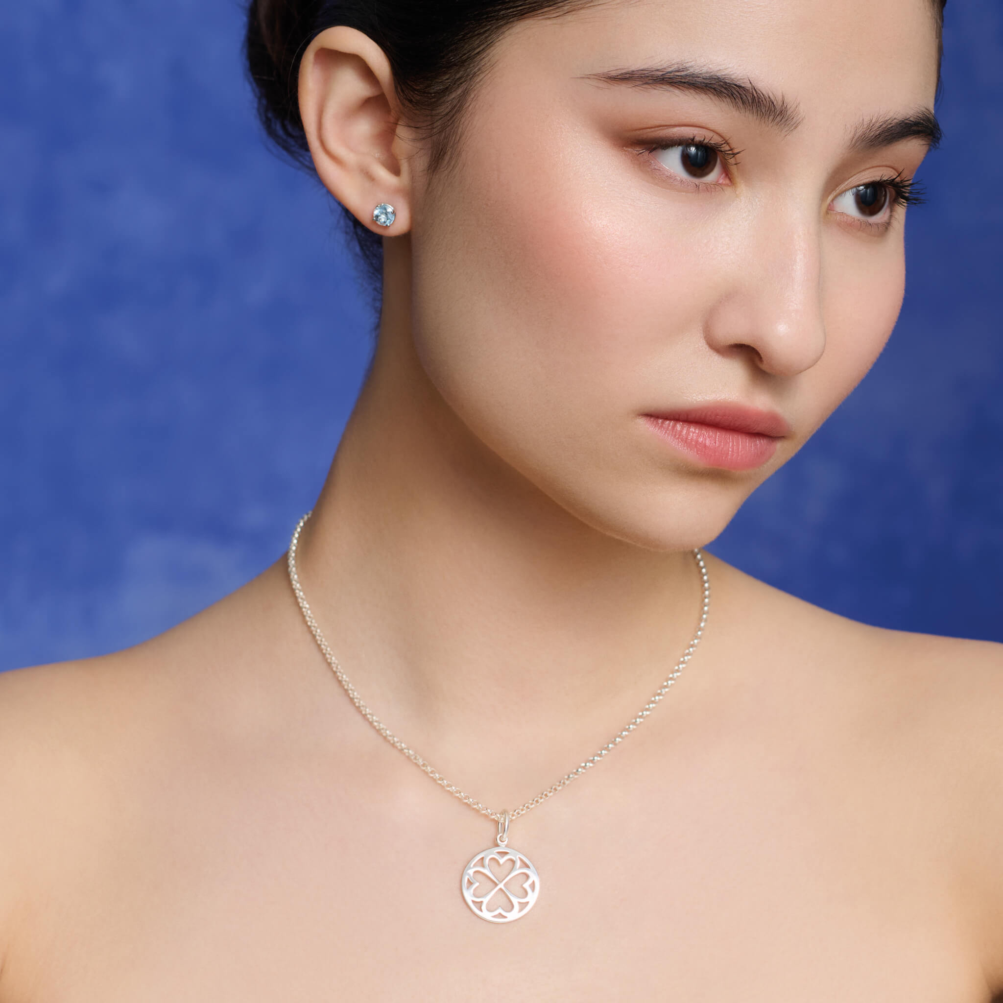 Model wearing handcrafted precious metal Klover pendant symbolising faith, hope, love and luck