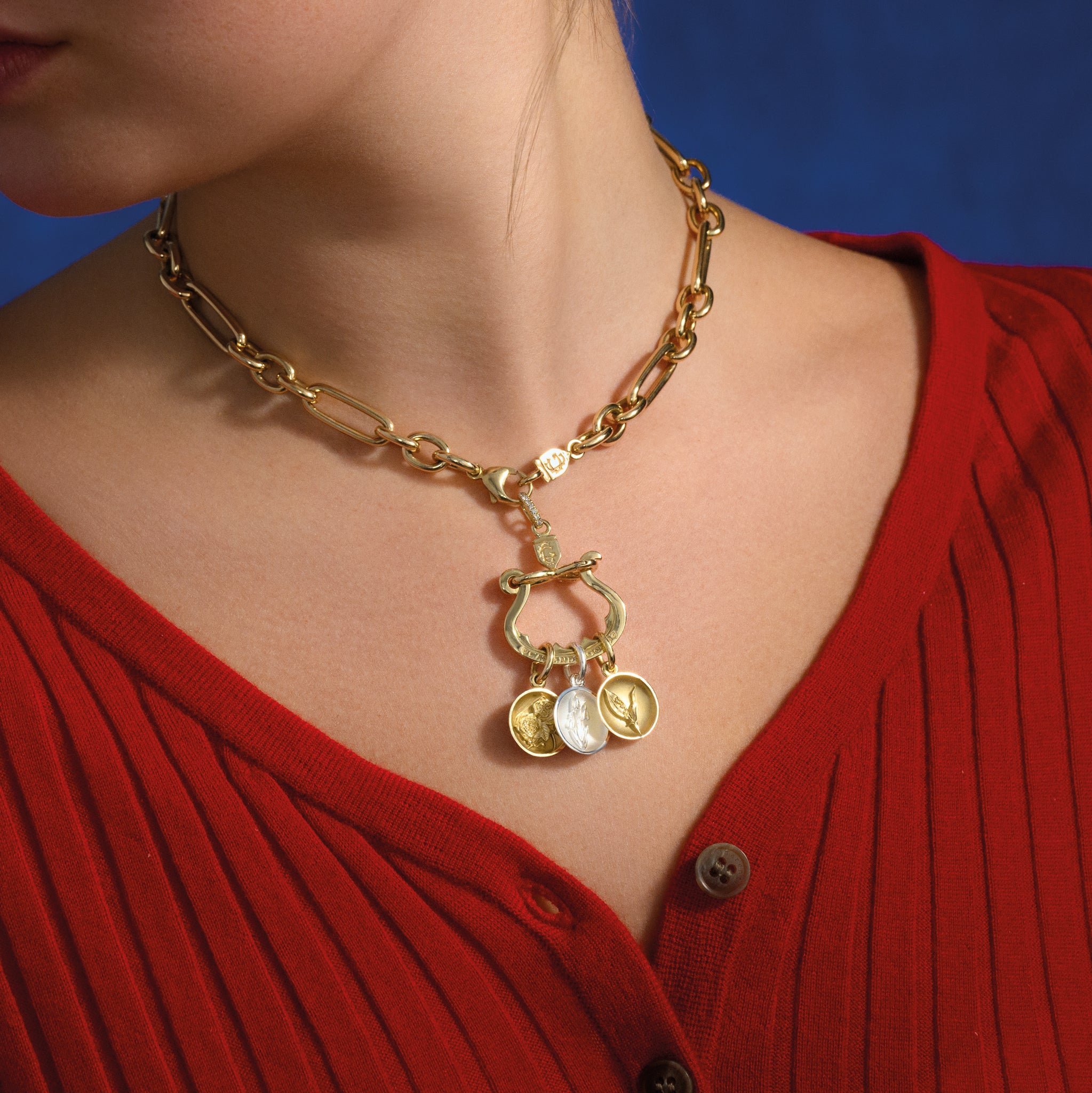 Model wearing a handcrafted yellow gold necklace pendant with three distinct charms elegantly suspended from it, set with diamond pave.