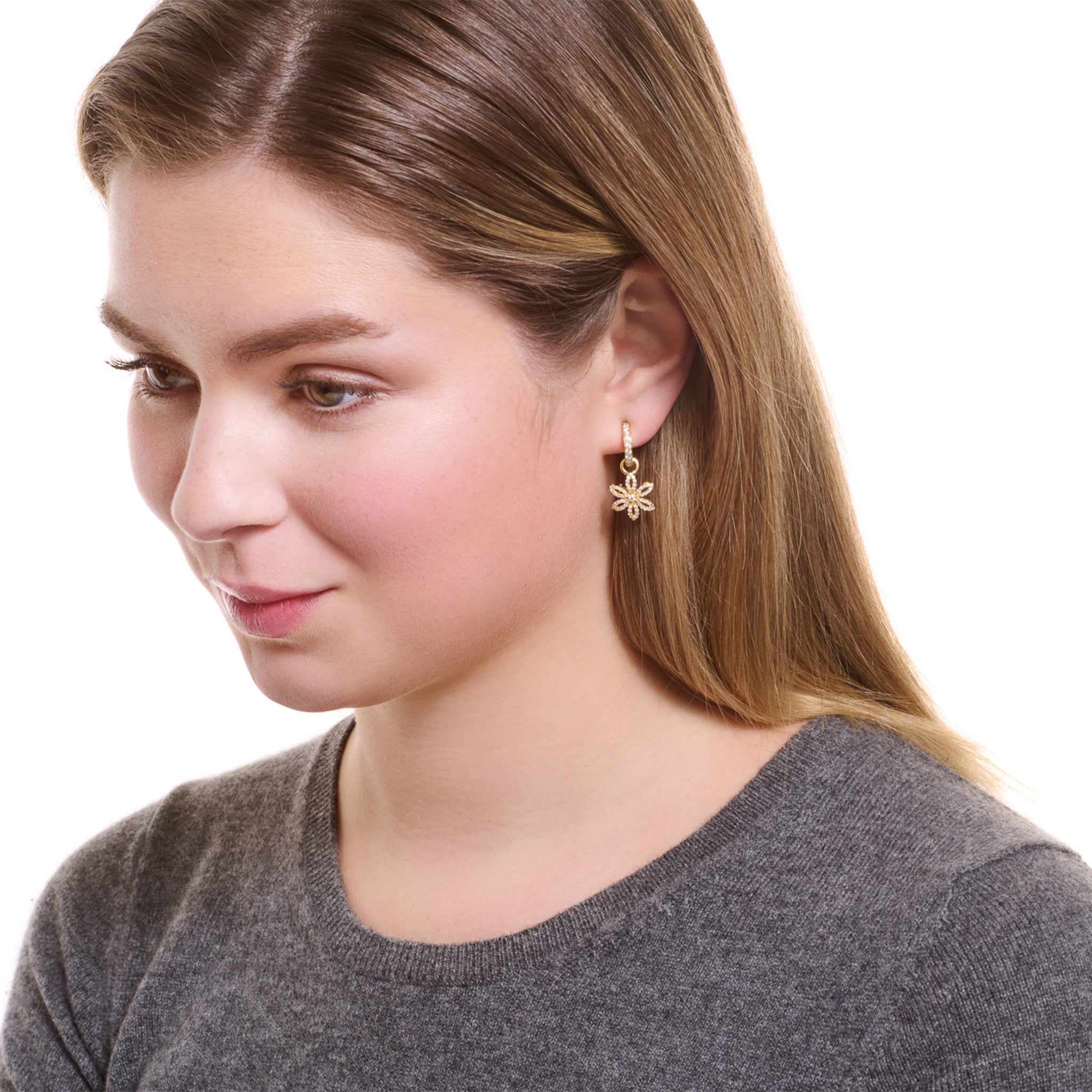 Model wearing handcrafted flower-shaped  earring drops in precious metal set with precious stones.