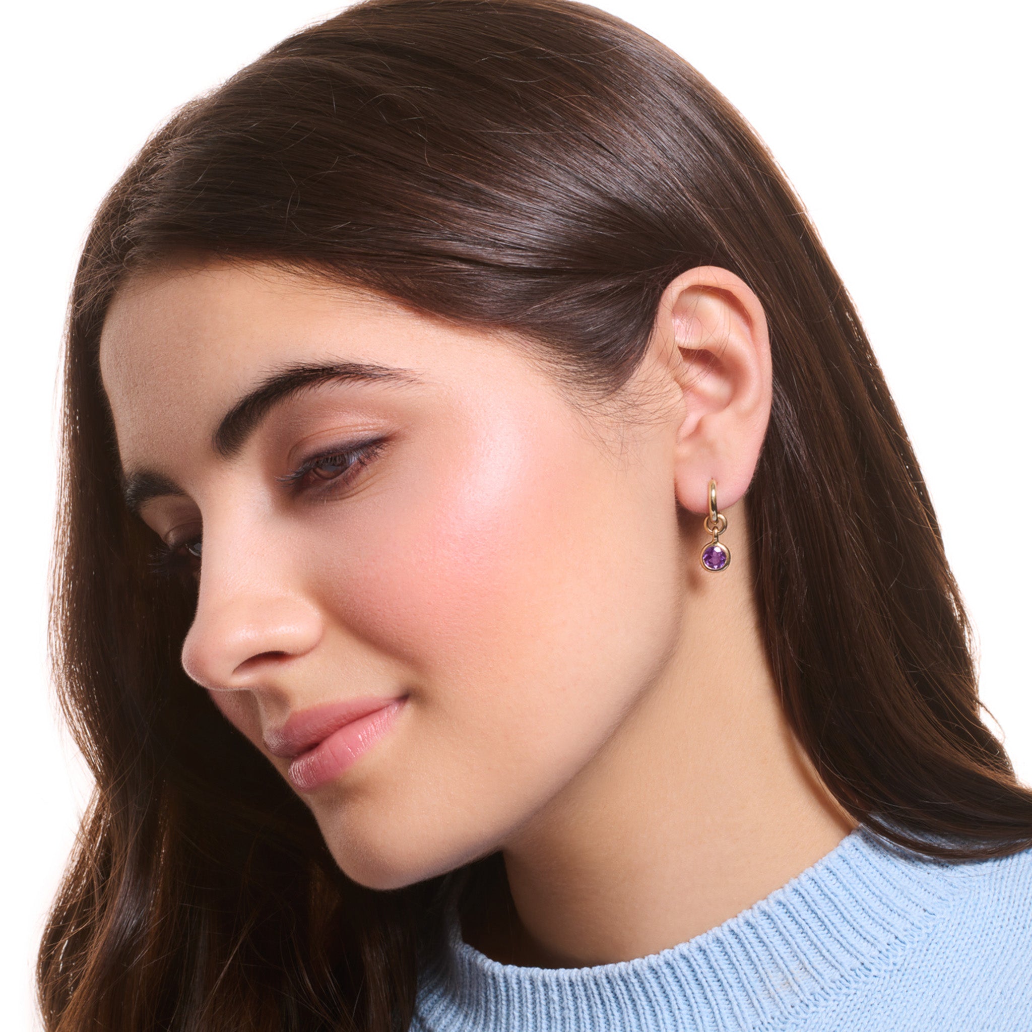 Model wearing handcrafted earring drops in precious metal with round precious stones.