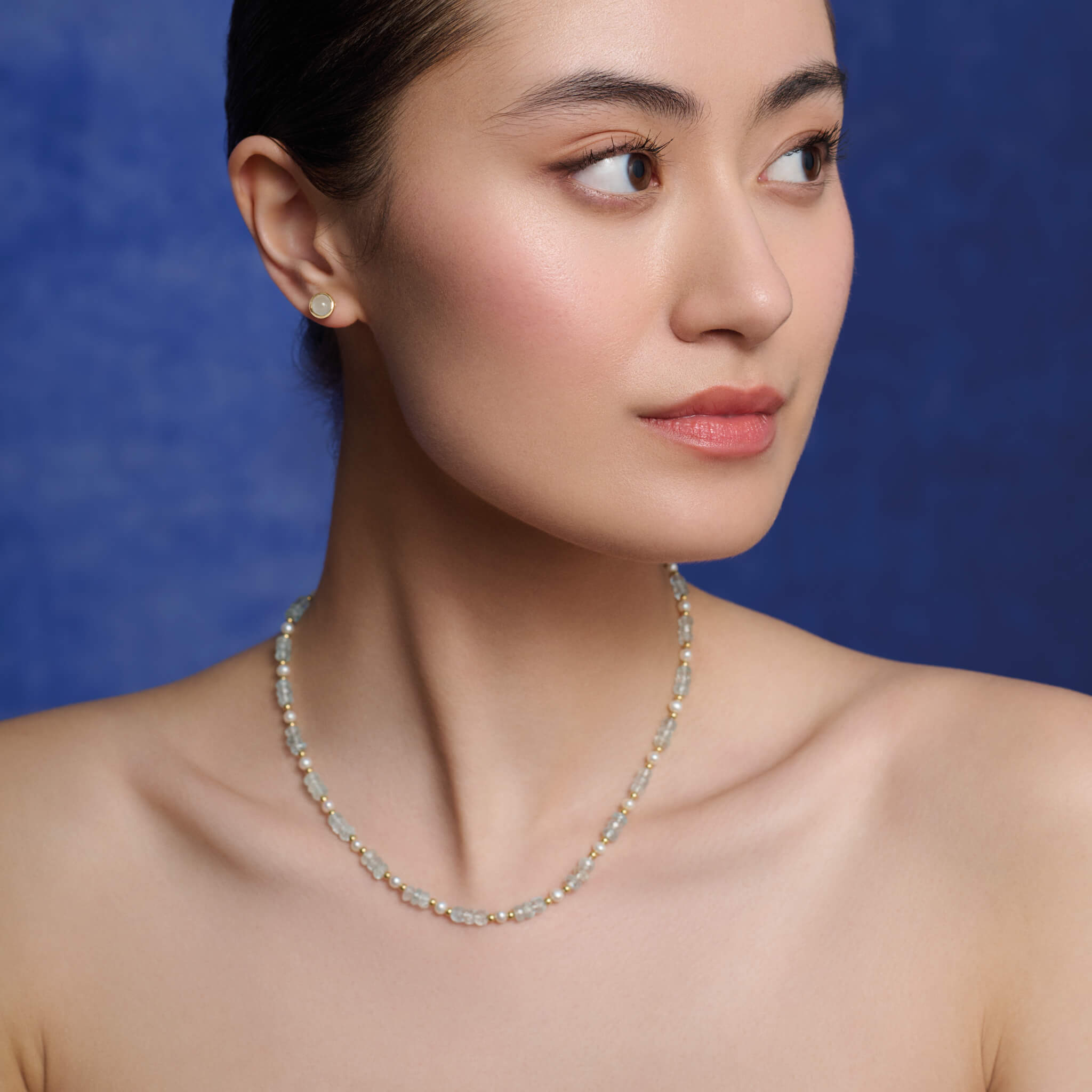 Model wearing a handcrafted yellow gold necklace with aquamarines and pearls.