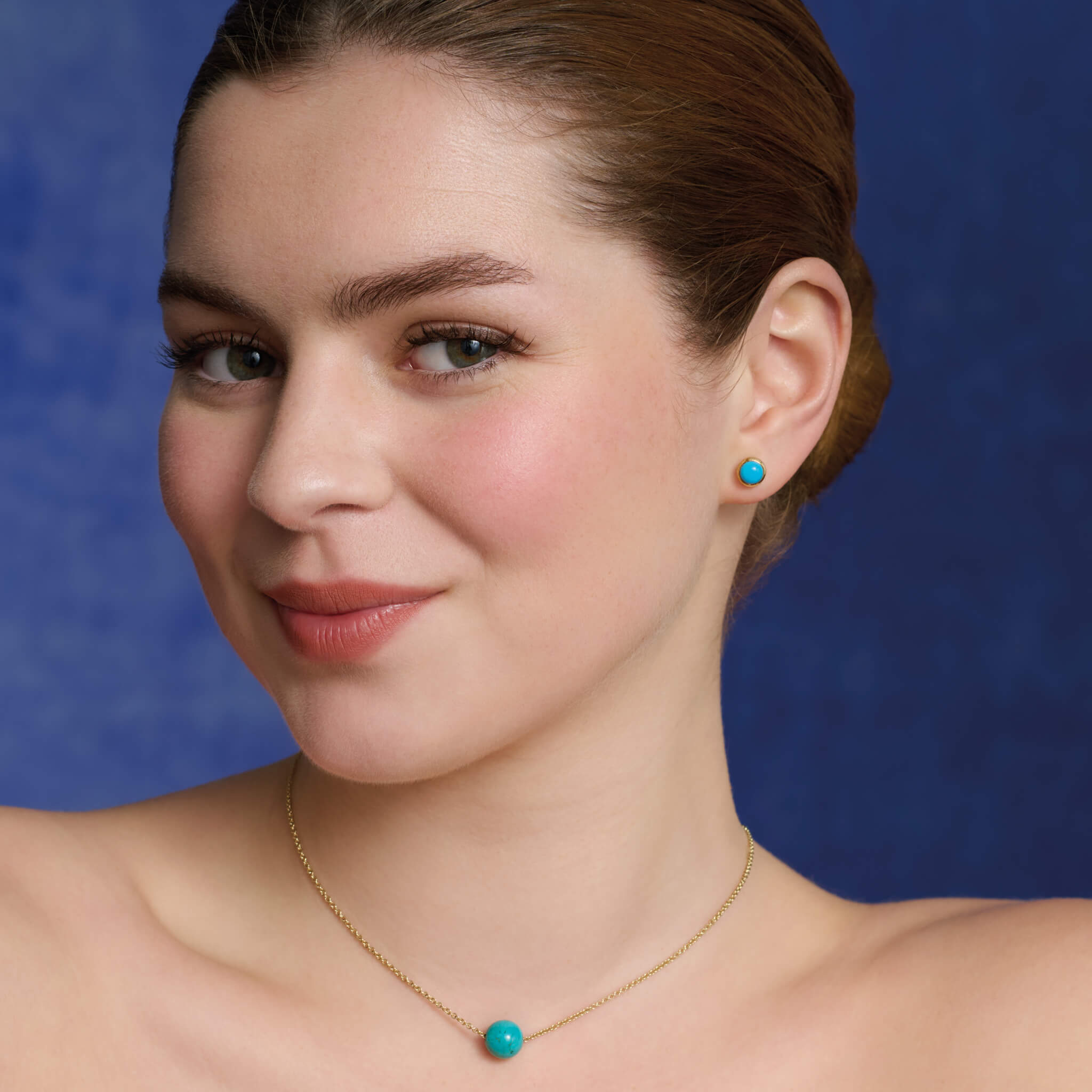 Model wears handcrafted 9ct yellow gold stud earrings featuring round turquoise, birthstone of December.