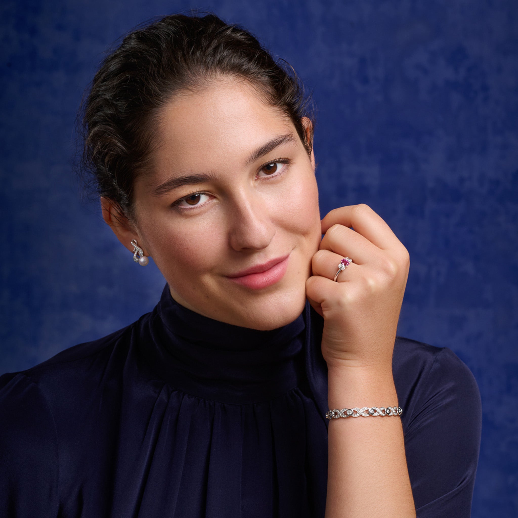 Model wears handcrafted 18ct white gold earrings with diamonds and a pearl drop in the shape of a sprig of rosemary.