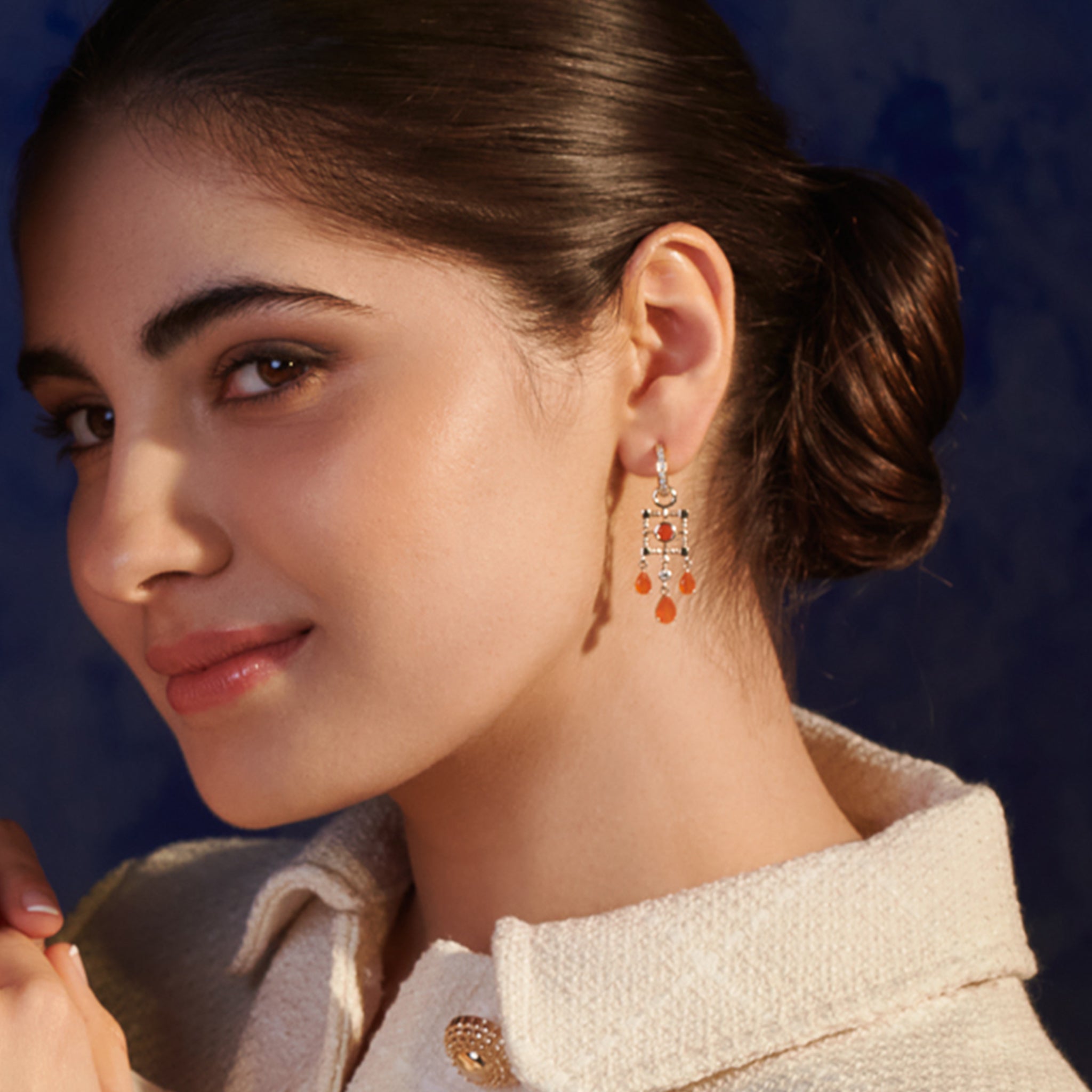 Model wearing handcrafted earring drops in precious metal featuring a teardrop-shaped design with precious stones.