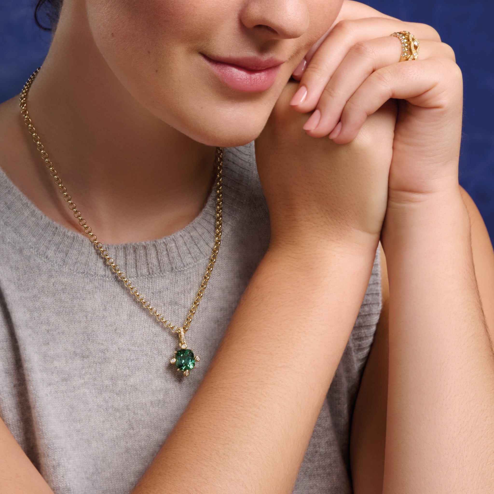 Model wearing handcrafted 9ct yellow gold pendant with facetted green gemstone set with four diamonds.