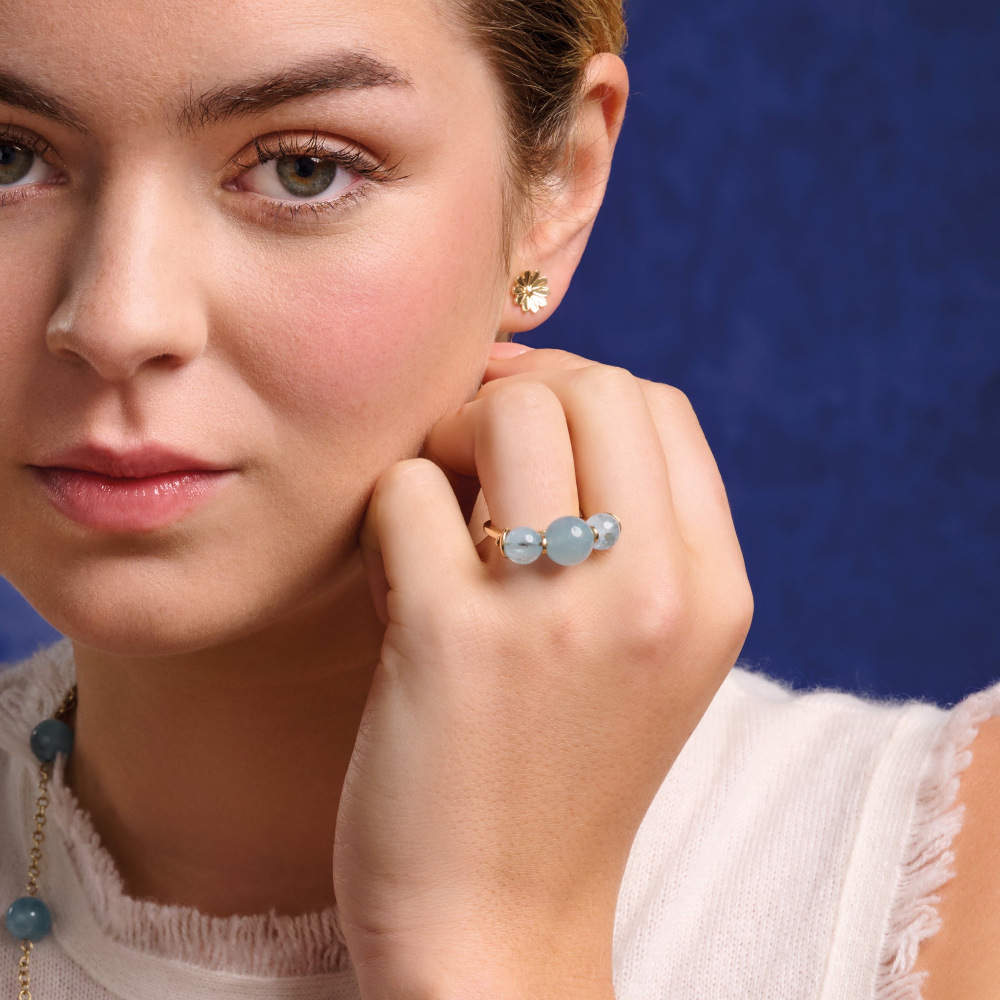 Model wearing a handcrafted 9ct gold ring featuring three aquamarine round beads.