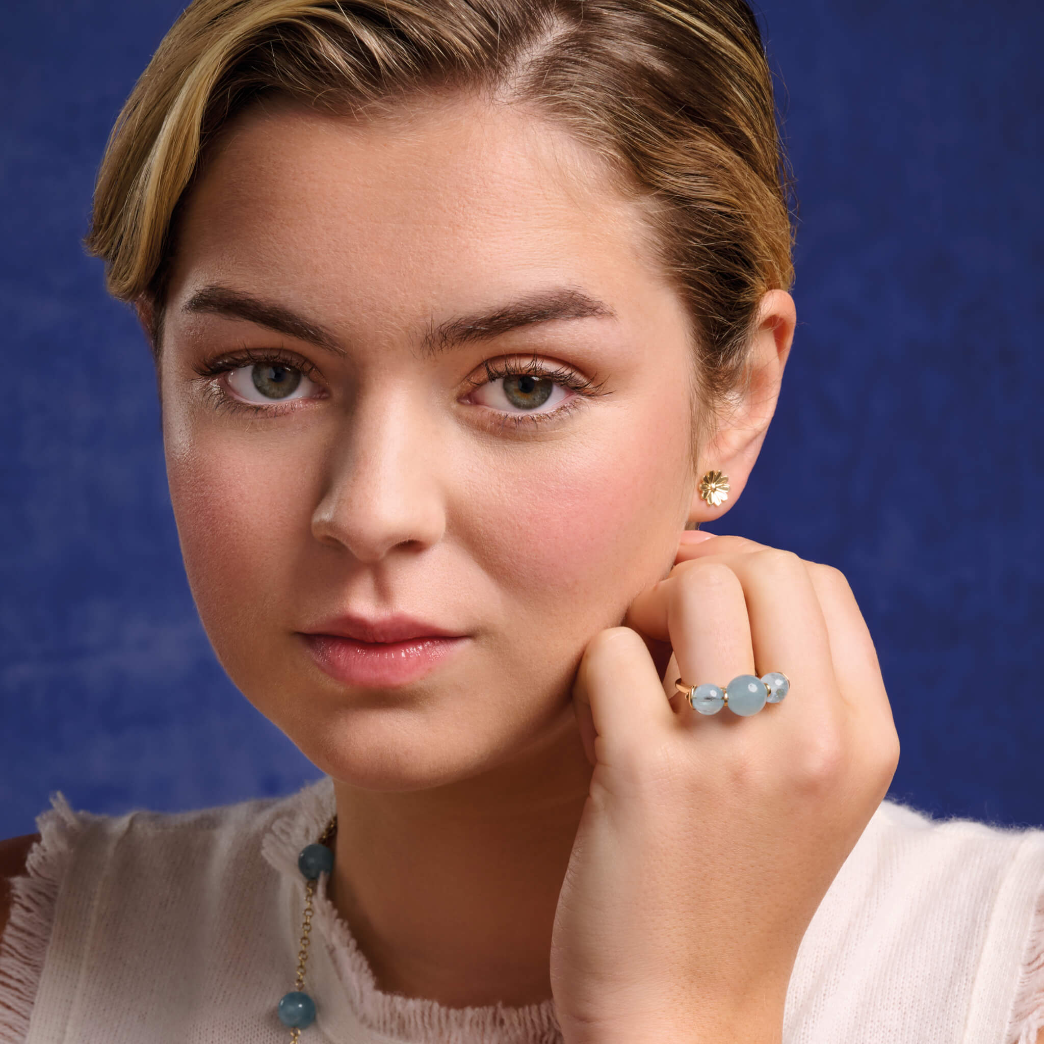 Model wears handcrafted 9ct yellow gold stud earrings in the shape of an anemone flower.