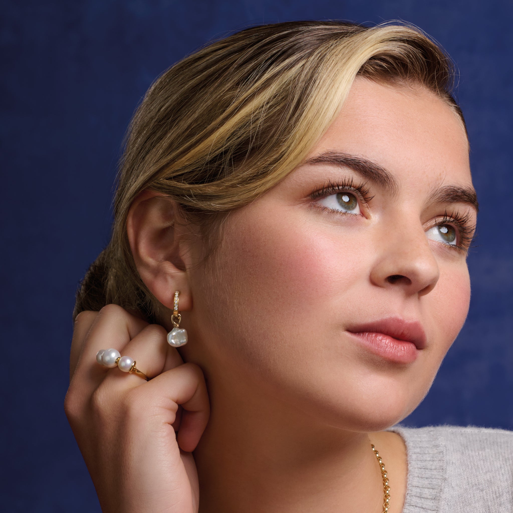 Model wearing a handcrafted 9ct gold ring featuring three white pearl beads.