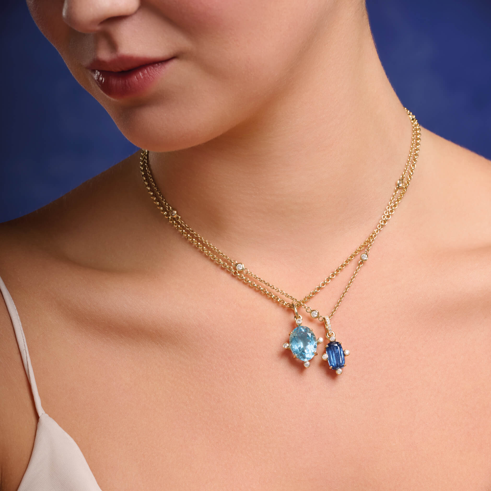 Model wears handcrafted Compass pendant in 18ct yellow gold with blue topaz set with four diamonds. On gold chain with diamonds.