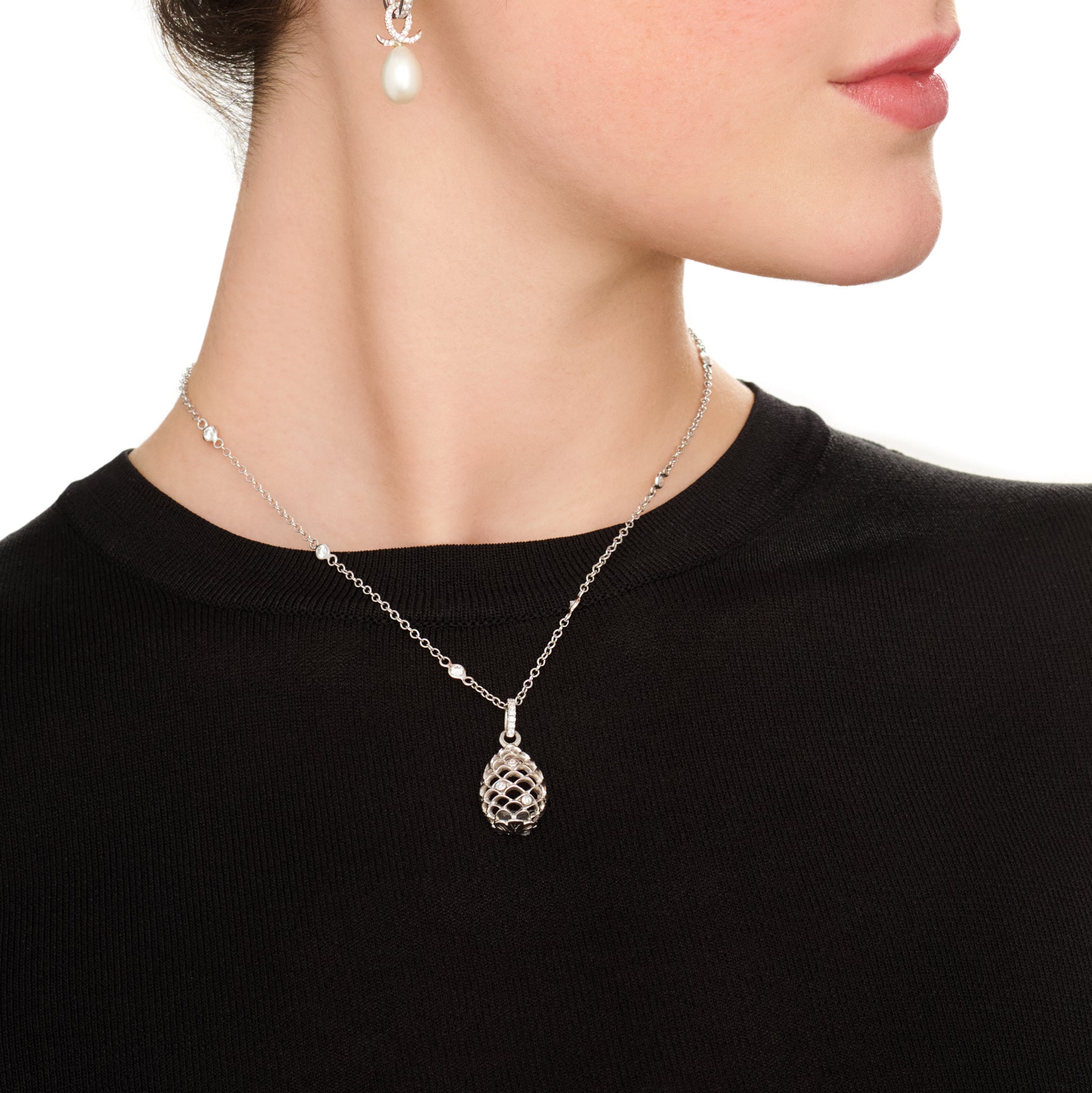 Model wearing a handcrafted white gold necklace pendant featuring a pinecone shape with diamonds, on a diamond pav� loop and a white gold chain with diamonds.