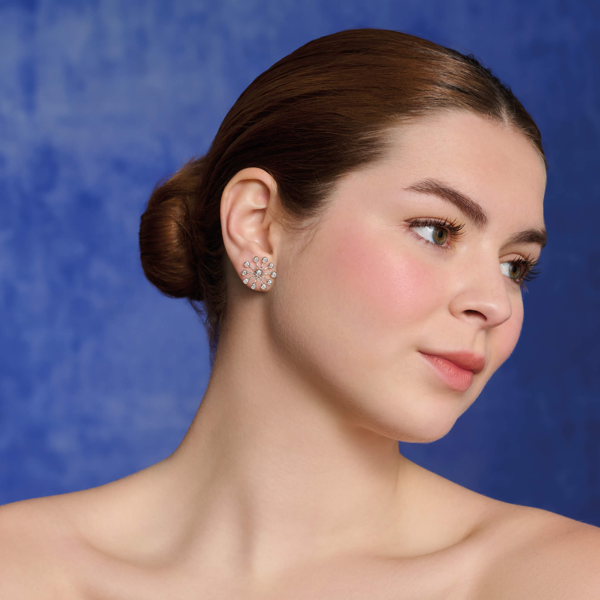 Model wearing handcrafted 18ct white gold earrings inspired by the delicate spurs of an astrantia flower, with diamonds set at the tip of each spur.