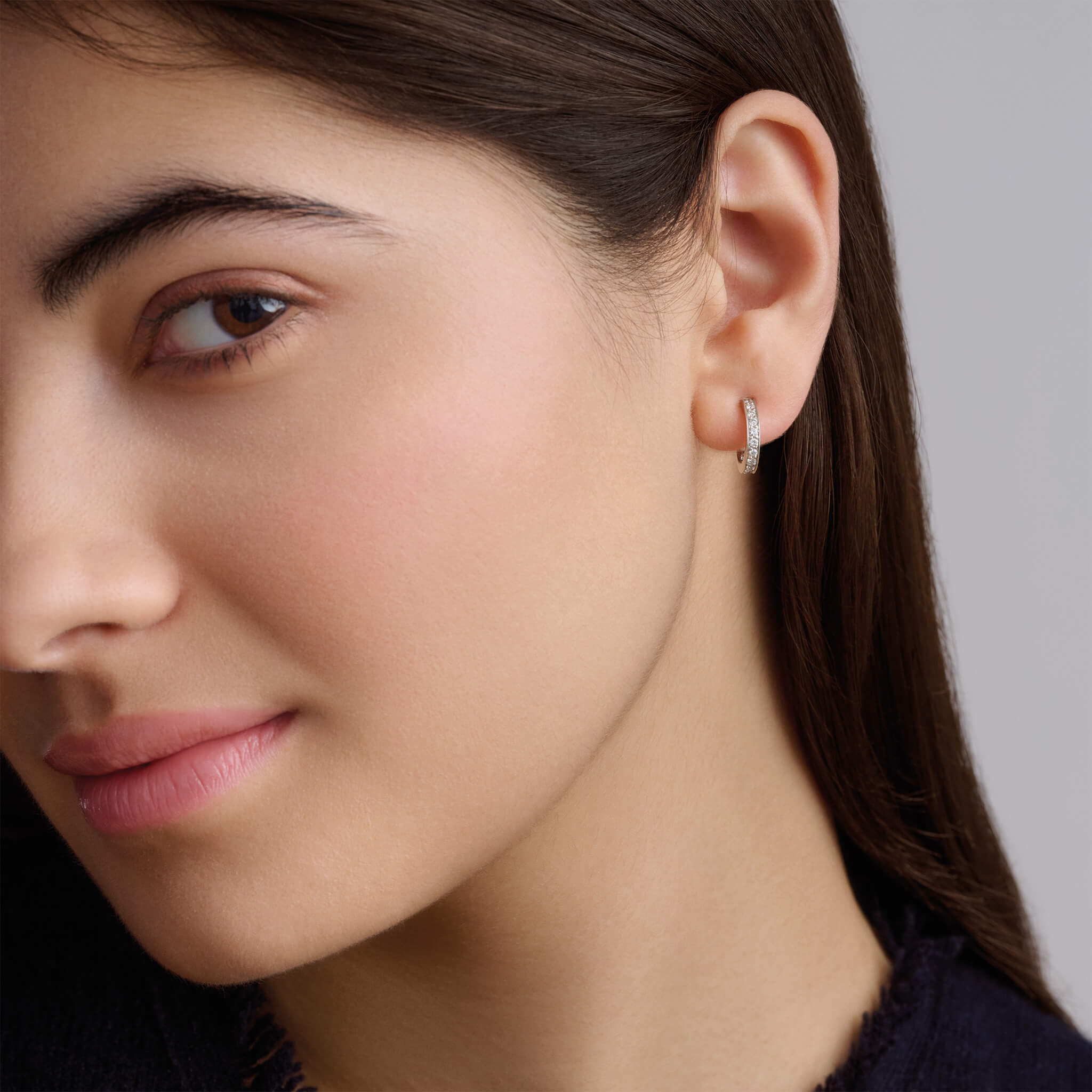 Model wearing a handcrafted 18ct white gold hoop earring set with small diamonds.
