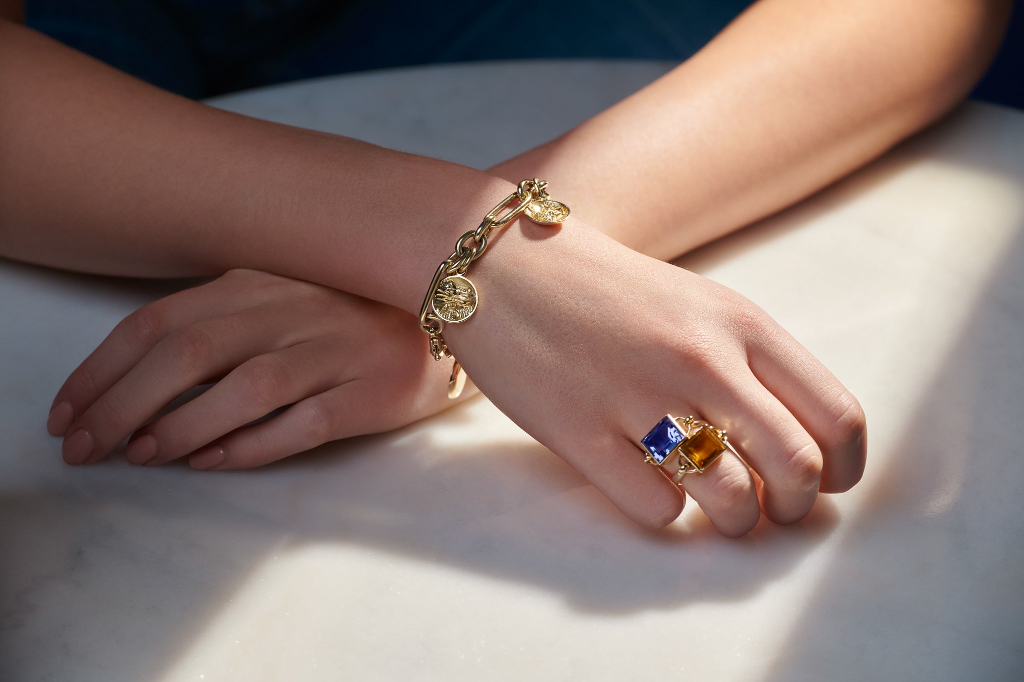 Model wearing handcrafted yellow gold rings and a bracelet featuring designs from the latest France collection.