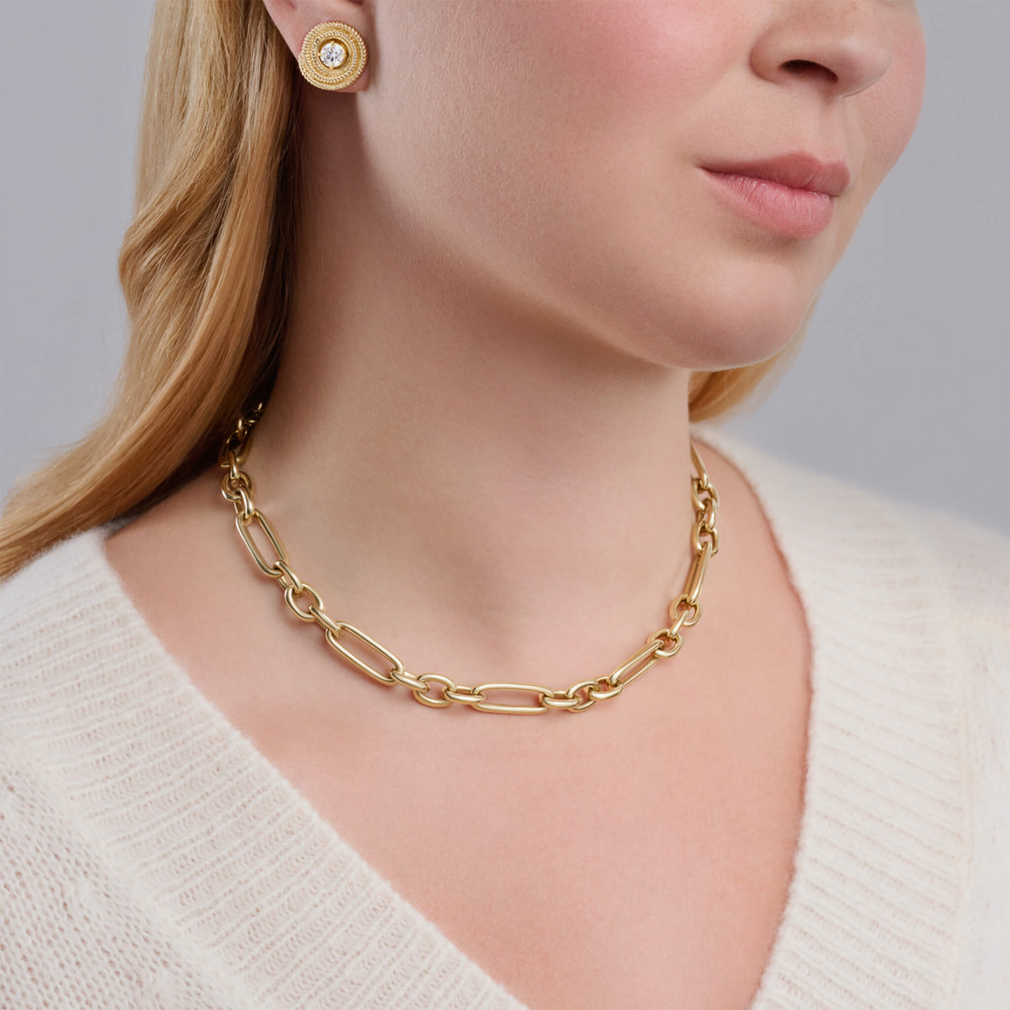 Model wearing a handcrafted yellow gold link necklace featuring chunky round and rounded rectangular links interconnected.