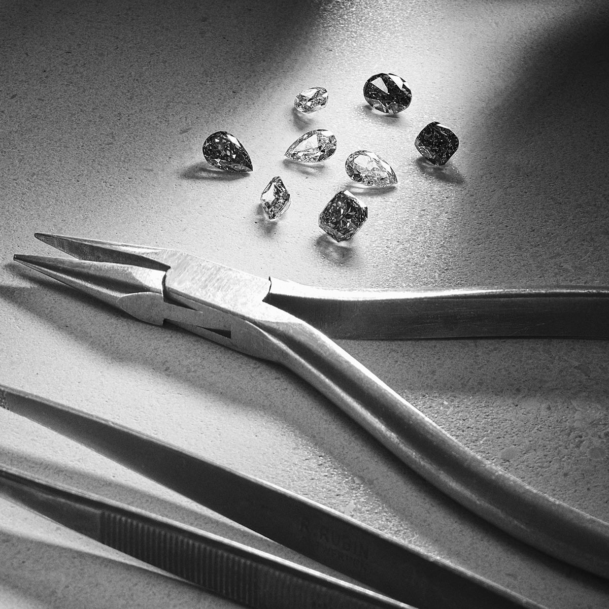 Workshop tools arranged beside loose precious stones, sourced and ready for setting in jewellery designs.