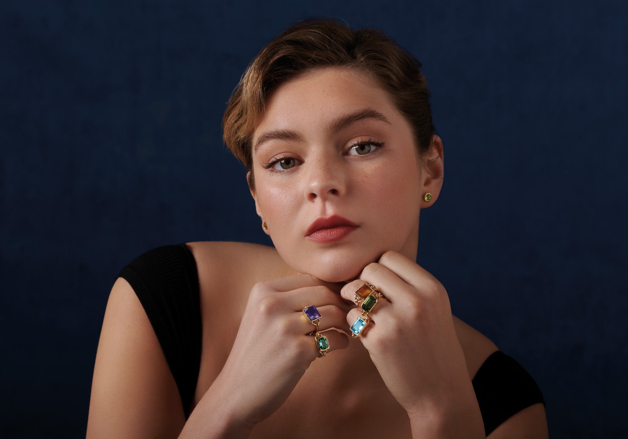 Model wearing handcrafted yellow gold rings featuring different birthstones.