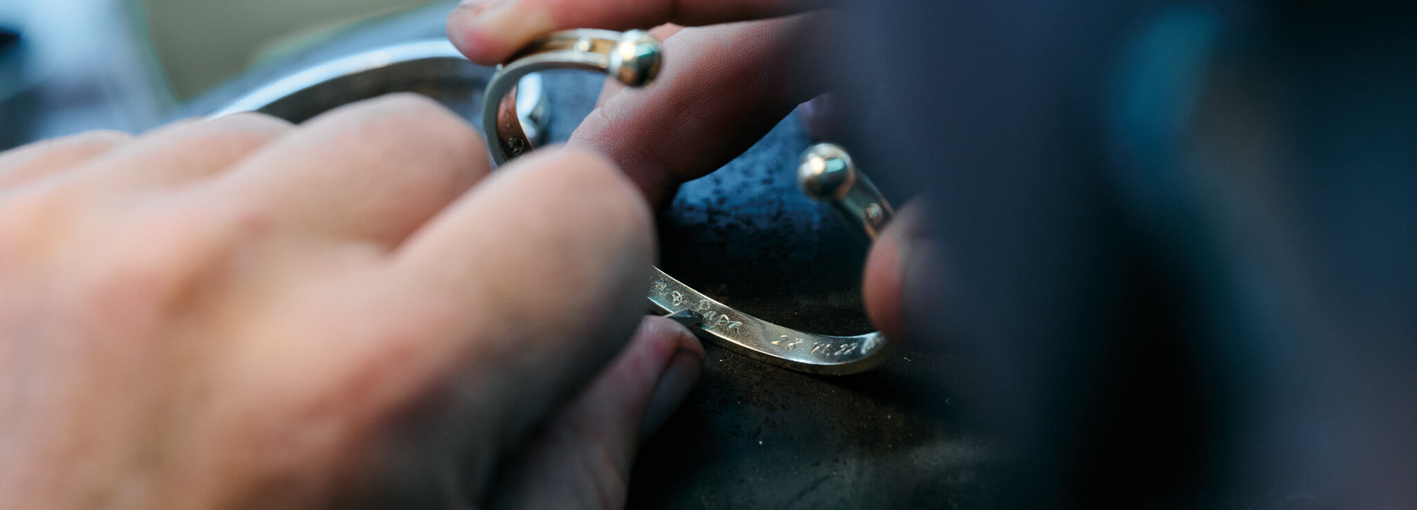 Close up of craftsman hand engraving a bracelet with a name.