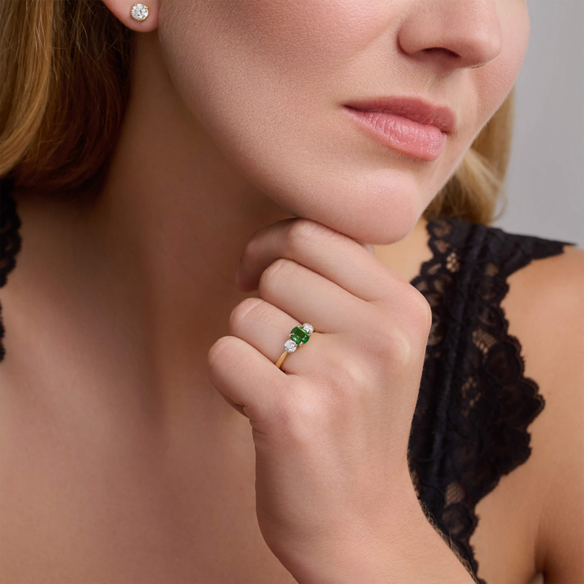 Handmade 18ct yellow gold engagement ring featuring a large, cushion cut emerald at its centre, surrounded by two smaller teardrop-shaped white diamonds.