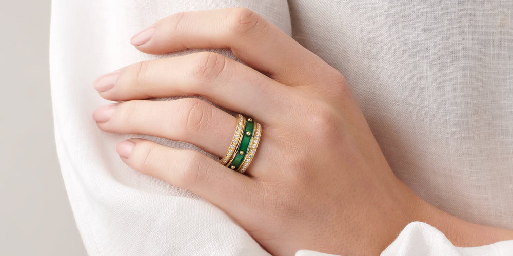 Model hand wearing emerald enamel Decimus ring stacked with two eternity rings