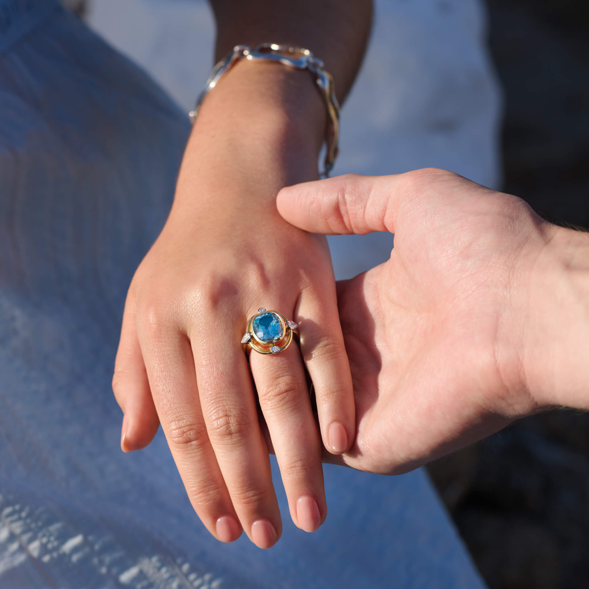 Model wearing handcrafted Compass engagement ring in yellow gold with aquamarine and diamond