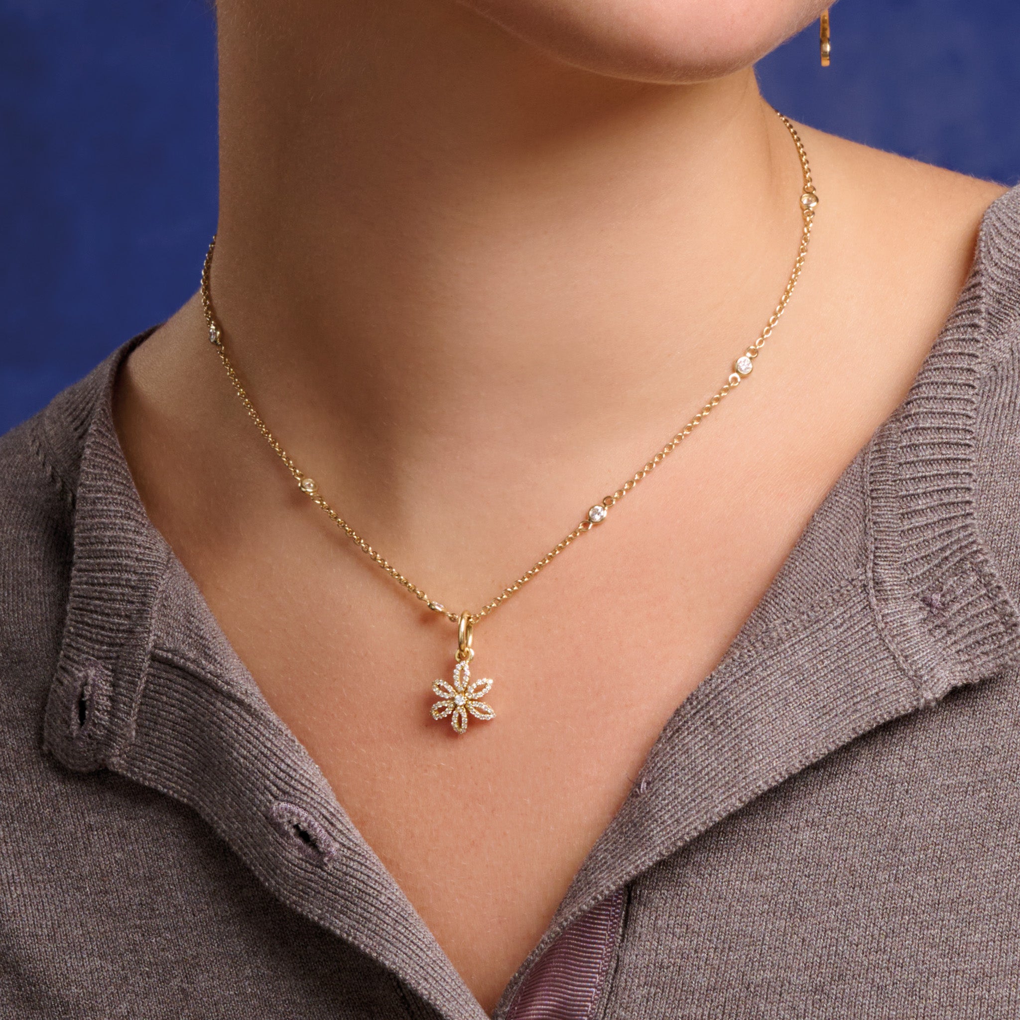 Model wearing handcrafted 18ct yellow gold flower necklace pendant with diamond pav? and central diamond, birthstone of April.